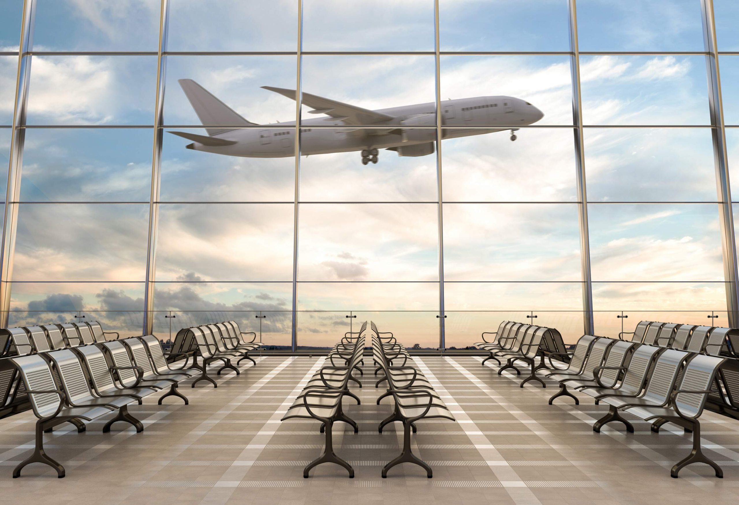 An airplane in flight passing by the large glass windows of the terminal.