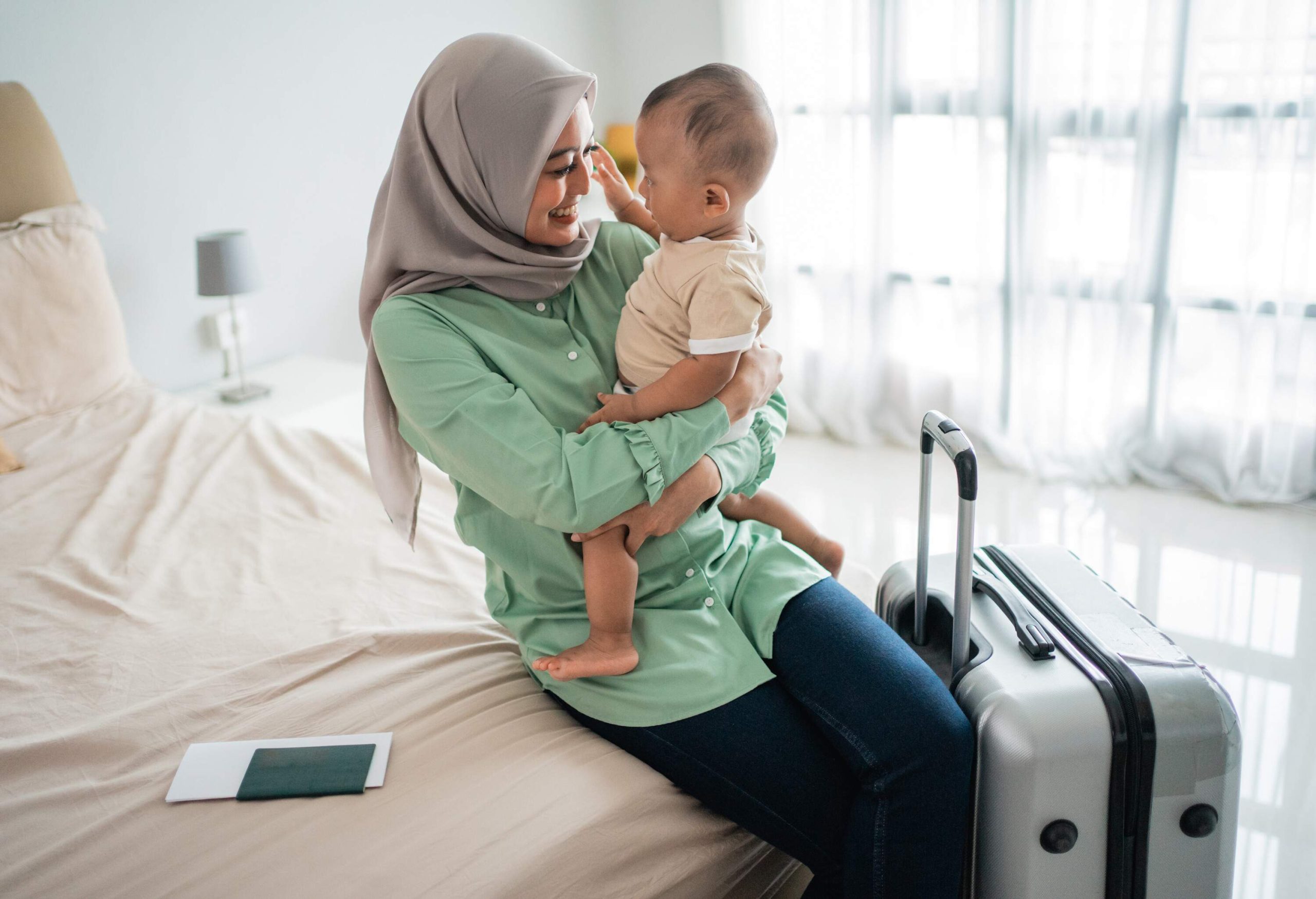 A Muslim mother carries her child in her arms as they sit in the bed.