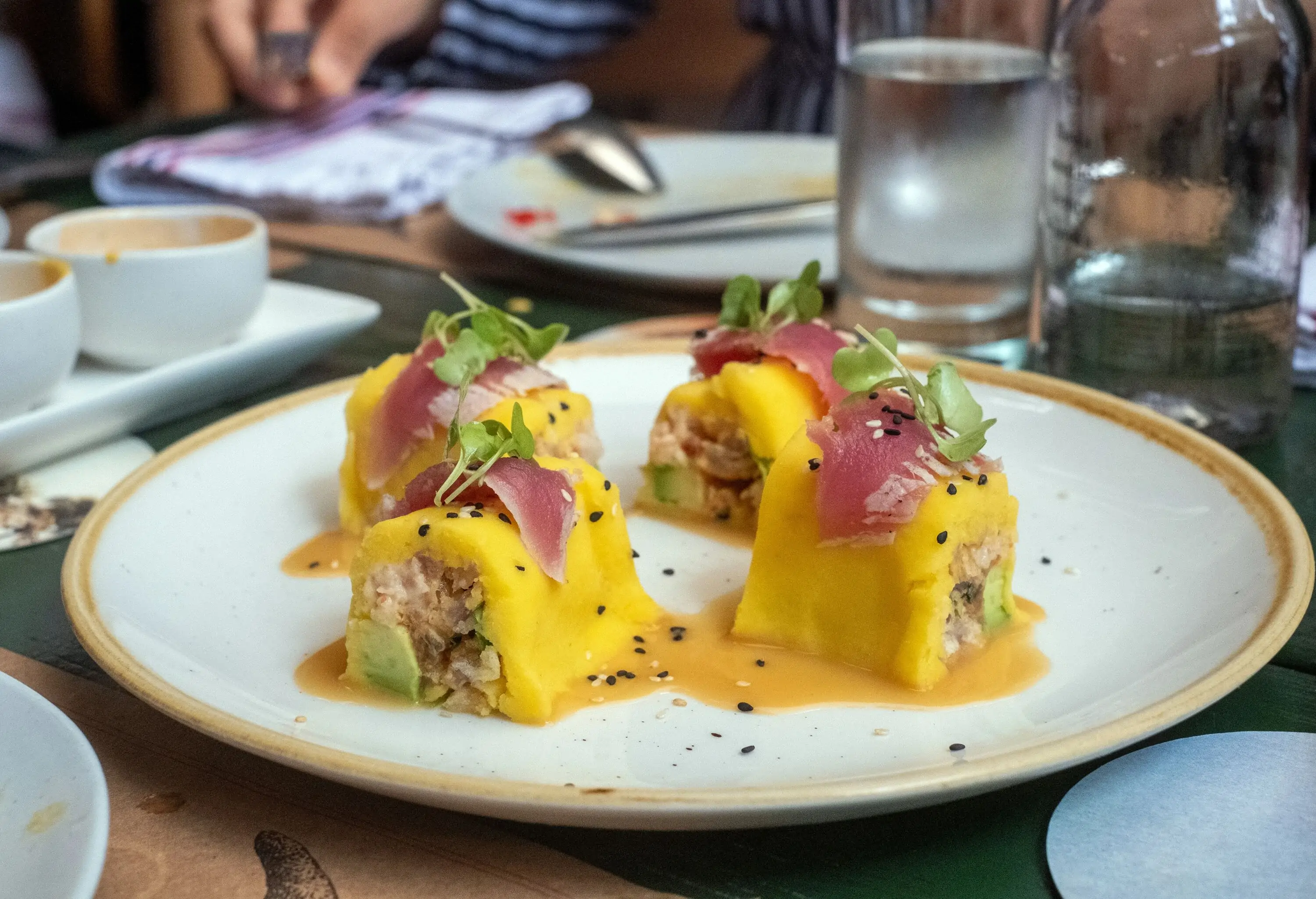 A delectable Peruvian sushi on a white plate with a golden rim.