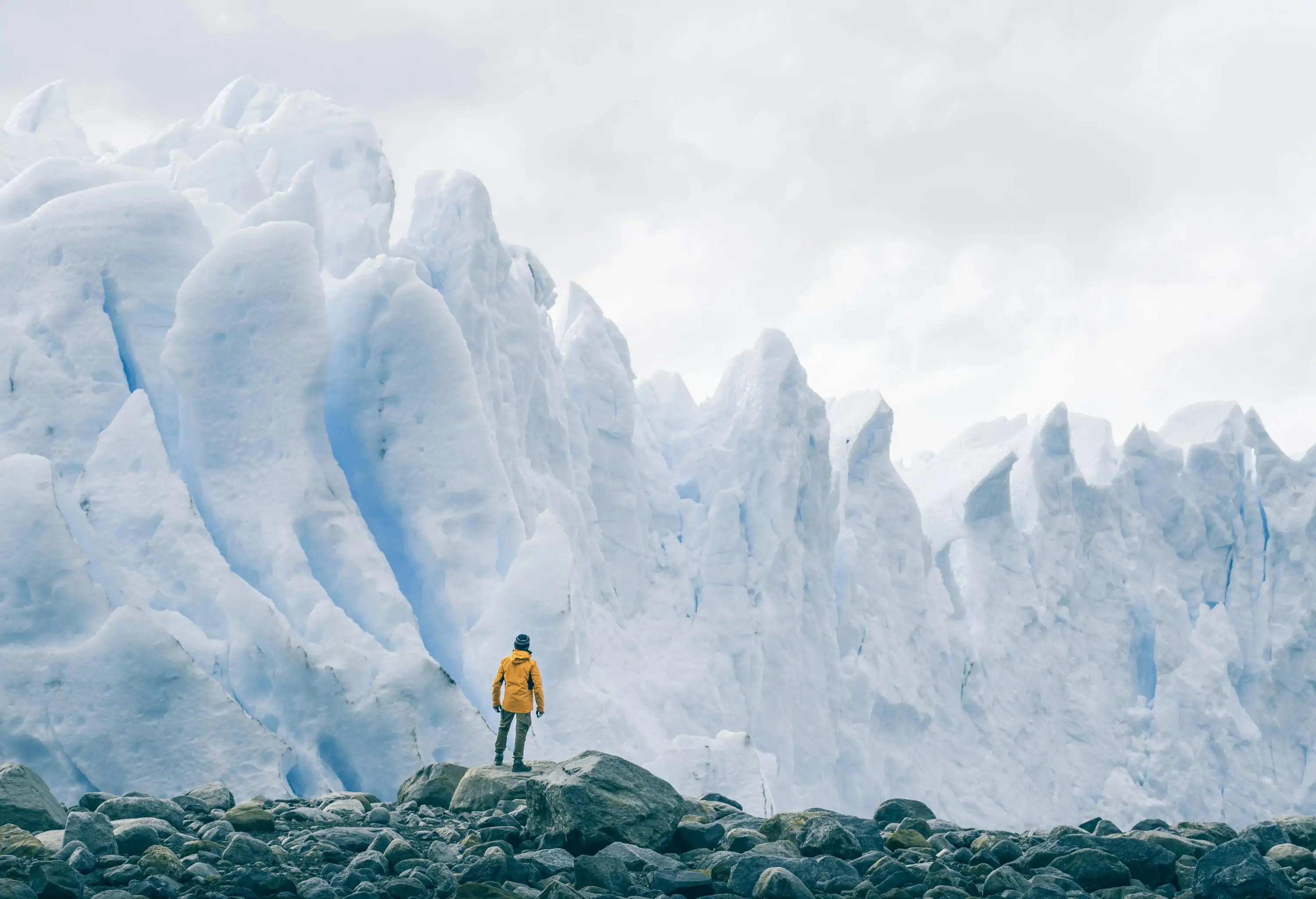 A lone figure gazes in awe at the majestic expanse of the Perito Moreno glacier, standing at the bottom and marvelling at its colossal size, immensity, and awe-inspiring beauty.