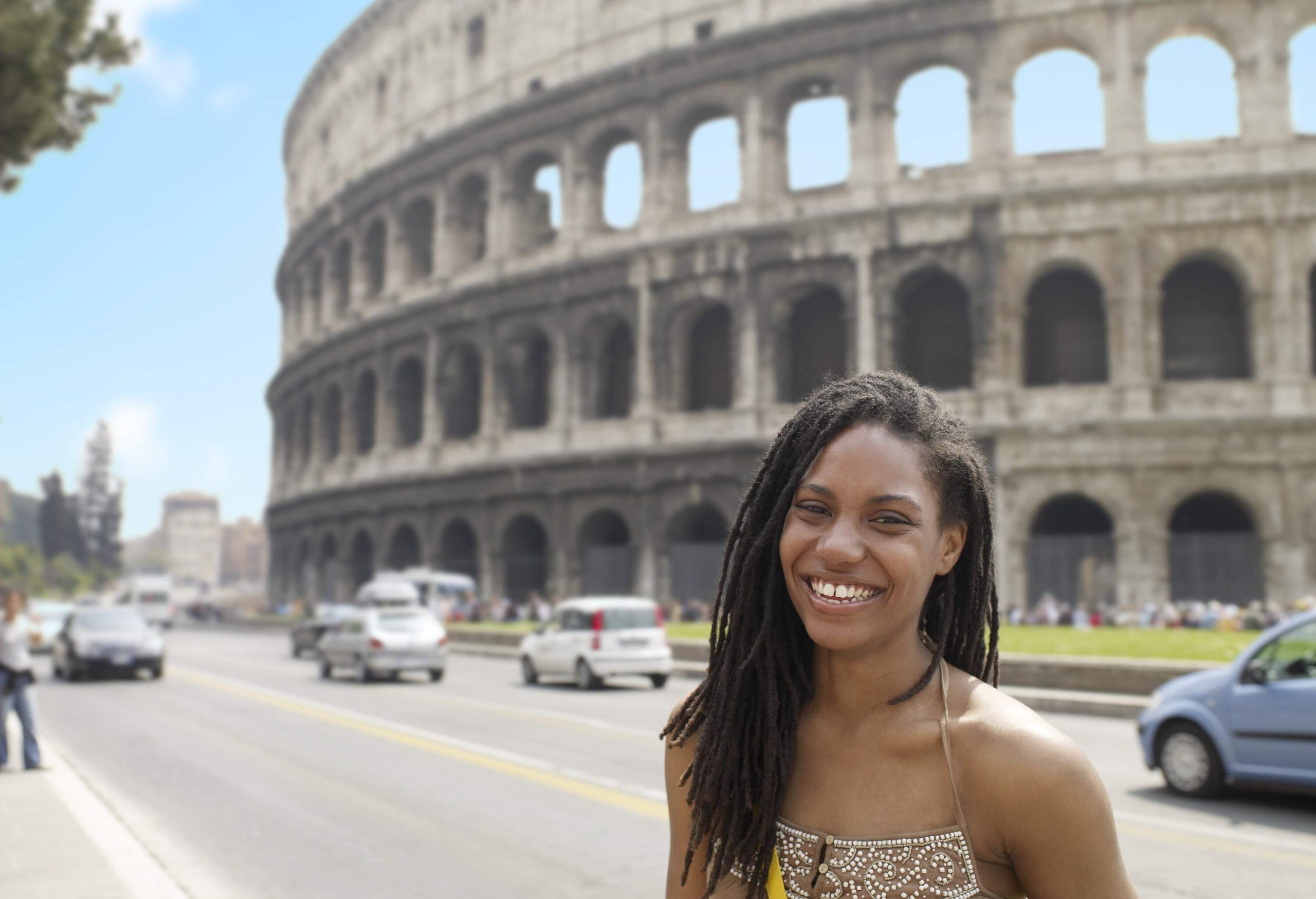 SMILING WOMAN STANDING IN FRONT OF THE COLISEUM ON A SUNNY SUMMER DAY