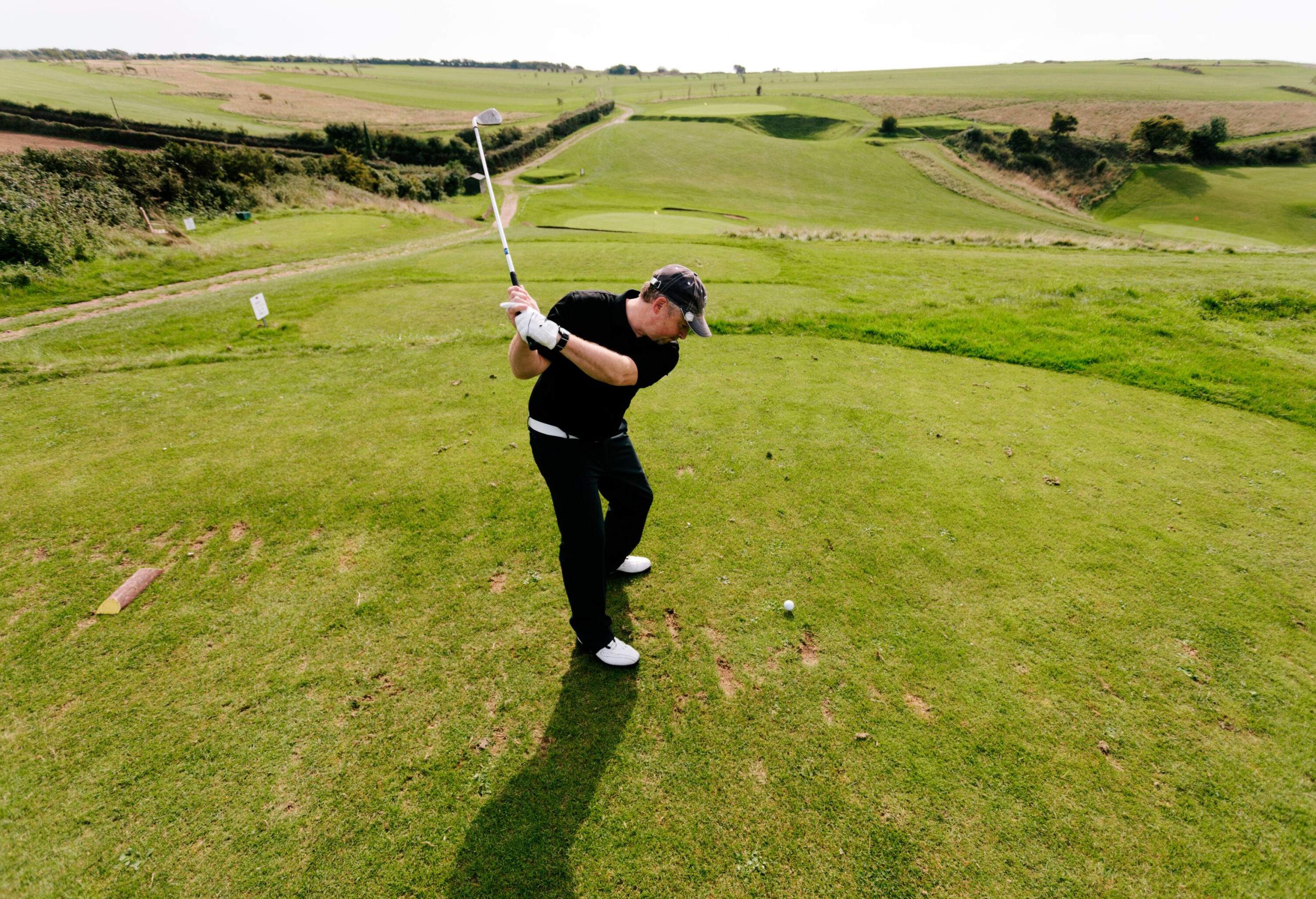A senior man playing golf on a putting green.