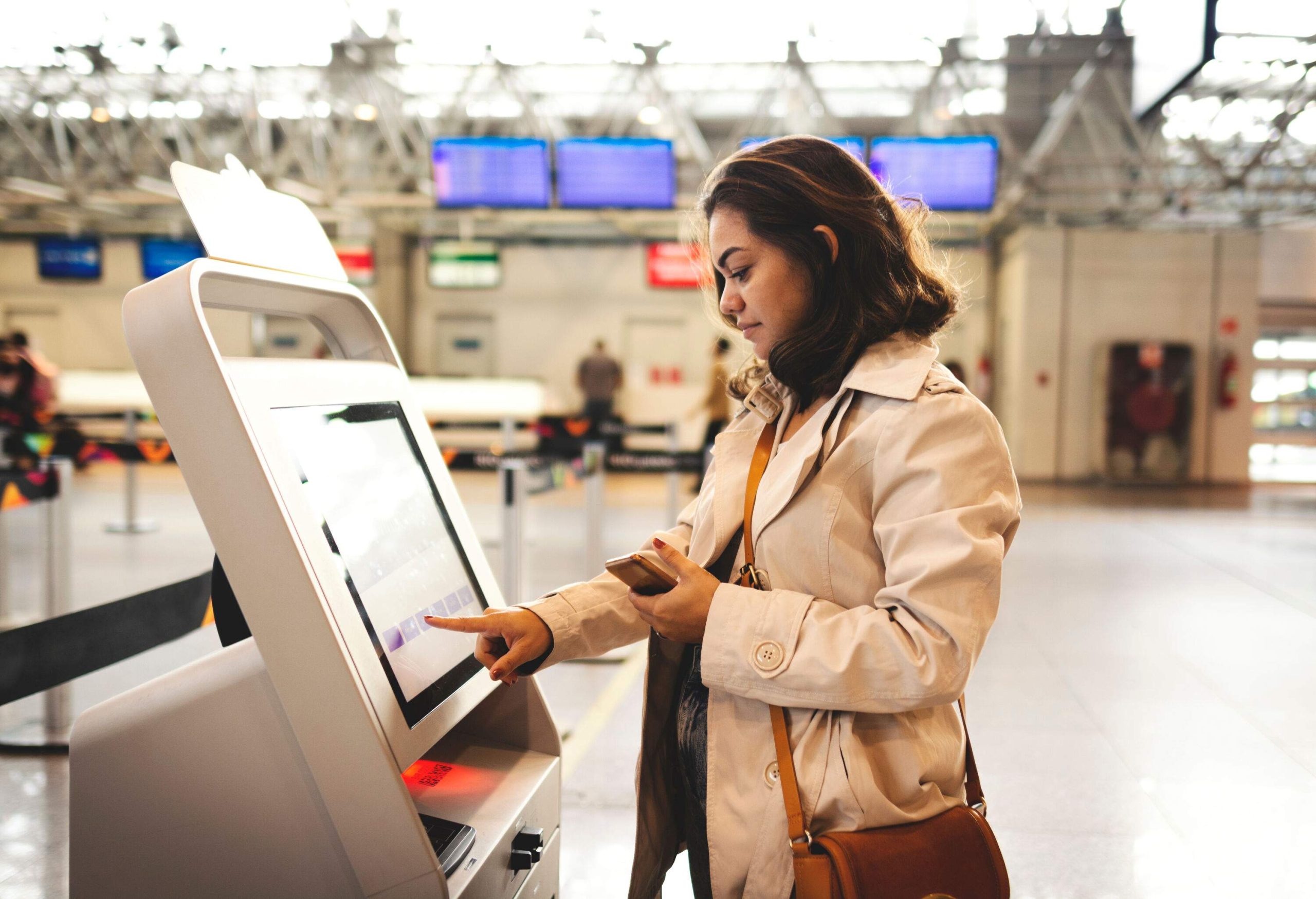 A woman using a modern kiosk in an airport.