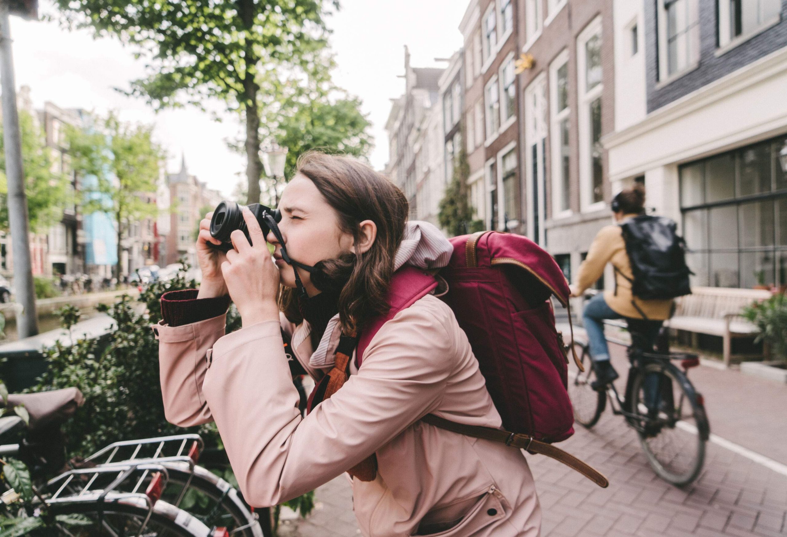 A woman taking pictures with a DSLR camera on a cobbled street.