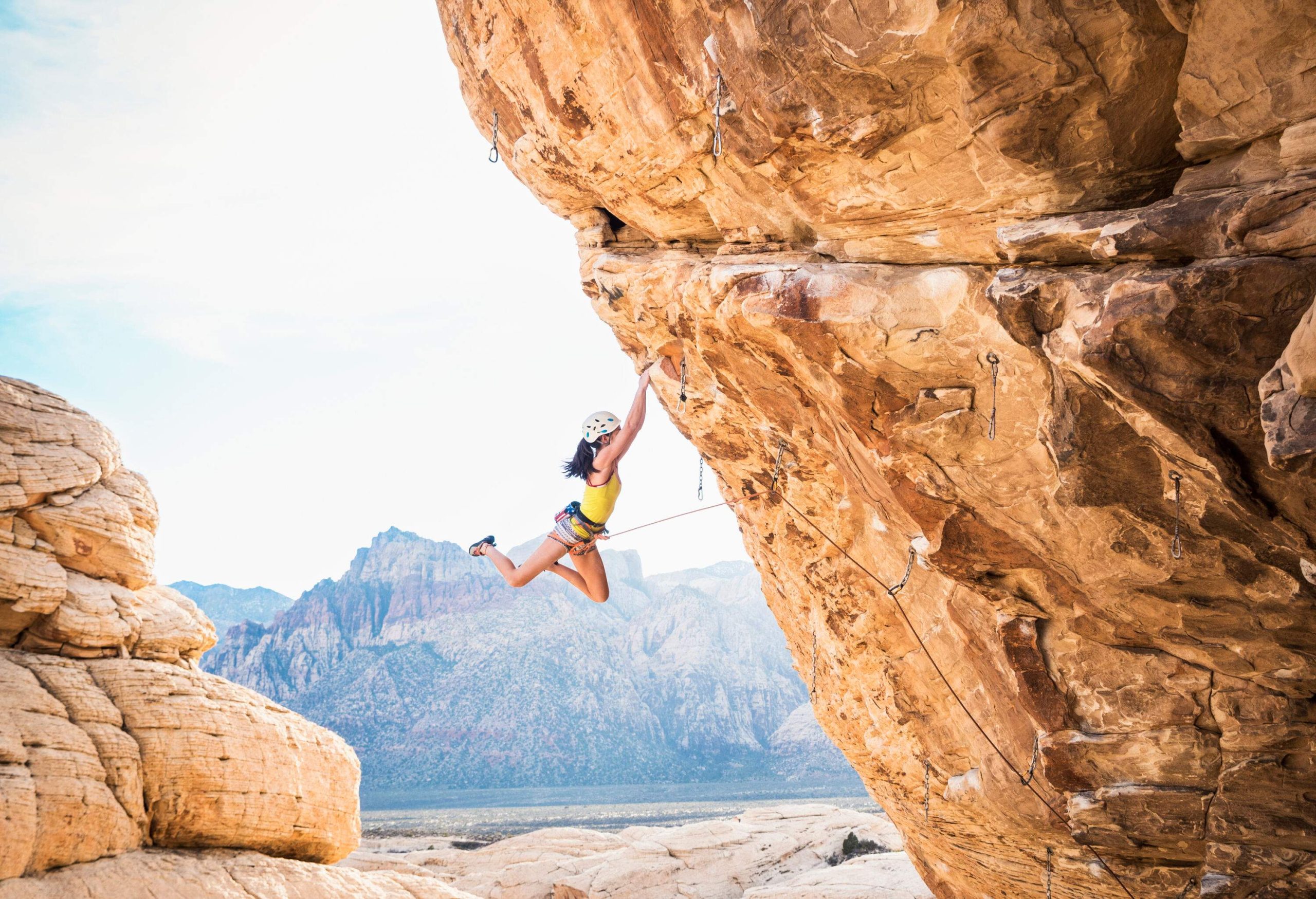 A woman fearlessly embraces the challenge of rock climbing as she ascends a towering cliff.