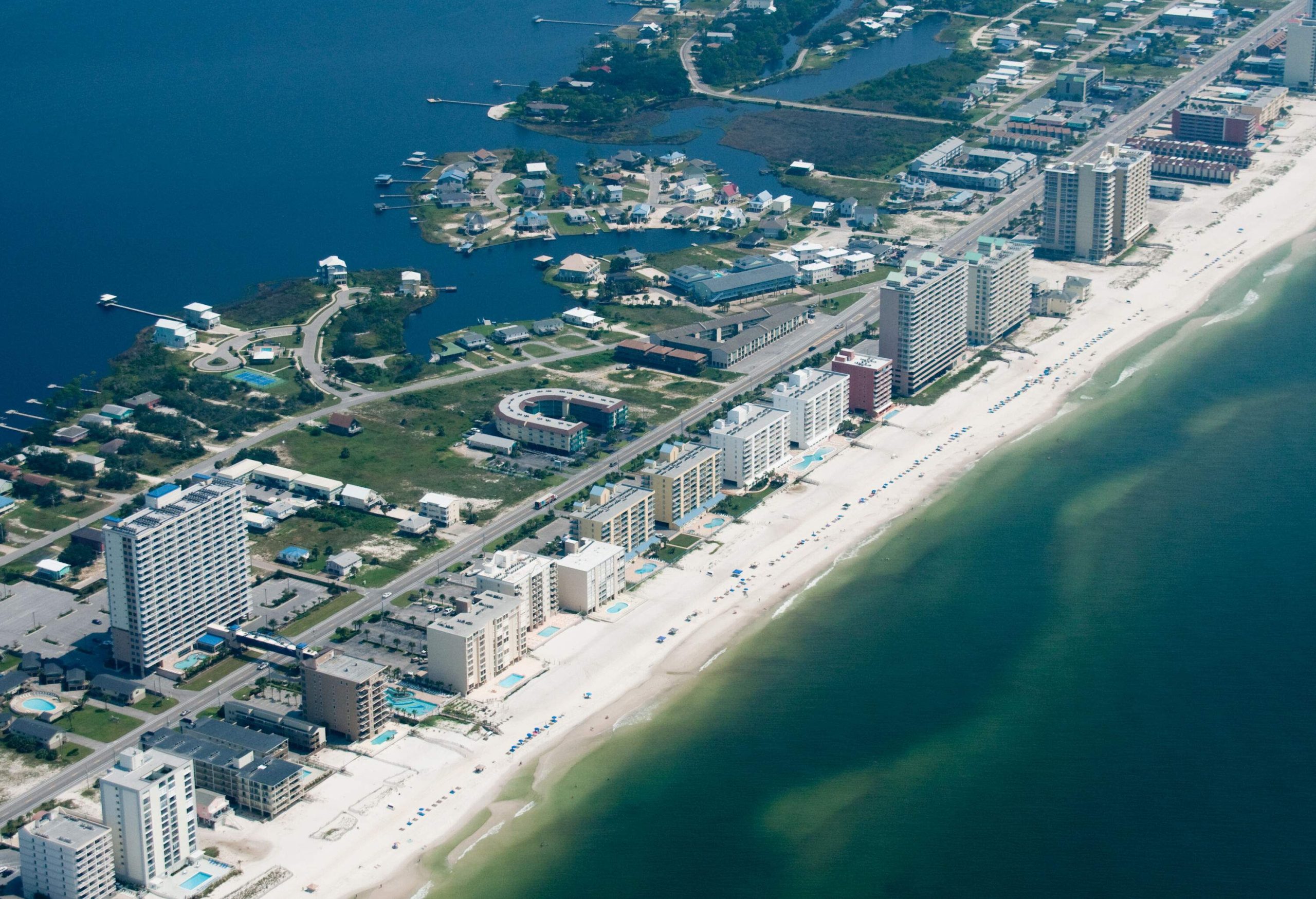 Tall buildings and tiny houses occupy the long strip of land surrounded by the sea.