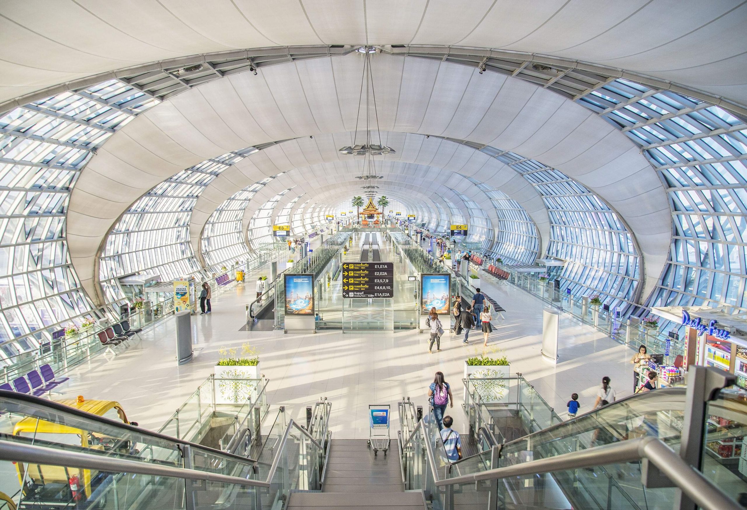 A descending escalator inside an airport terminal with glass walls.