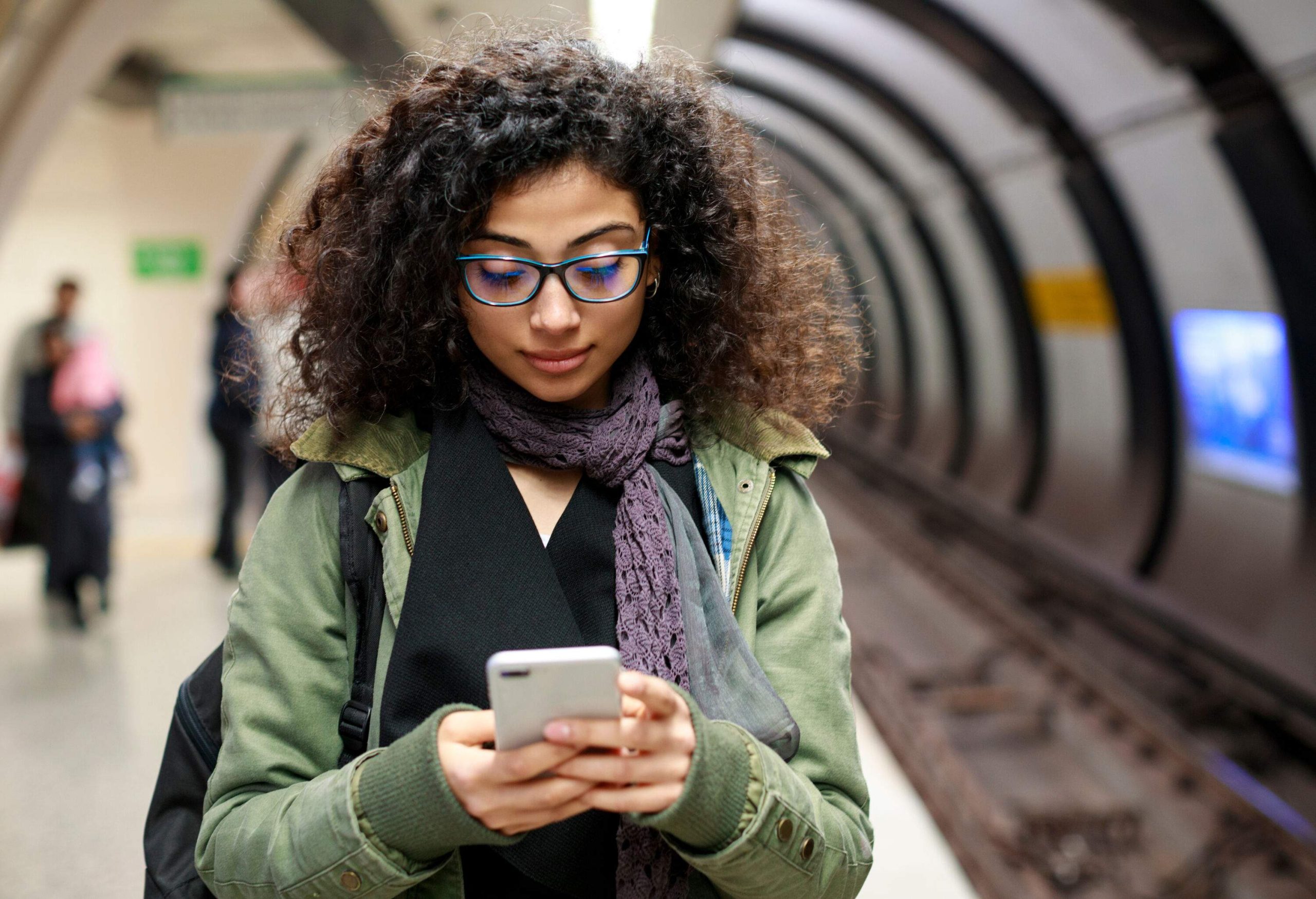 A young lady uses her mobile phone while in a subway station.