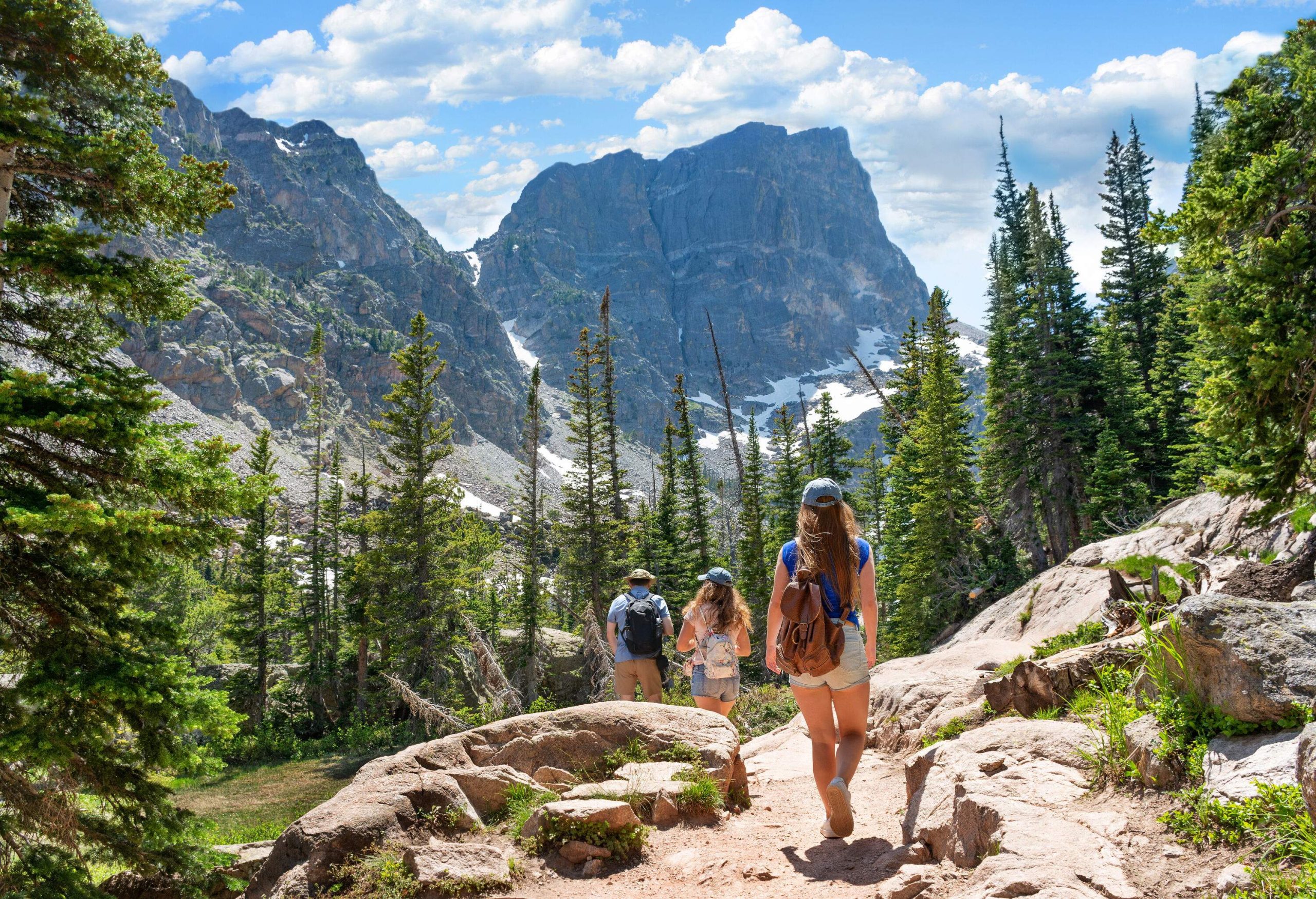 A father leads his two daughters hiking in the mountains.