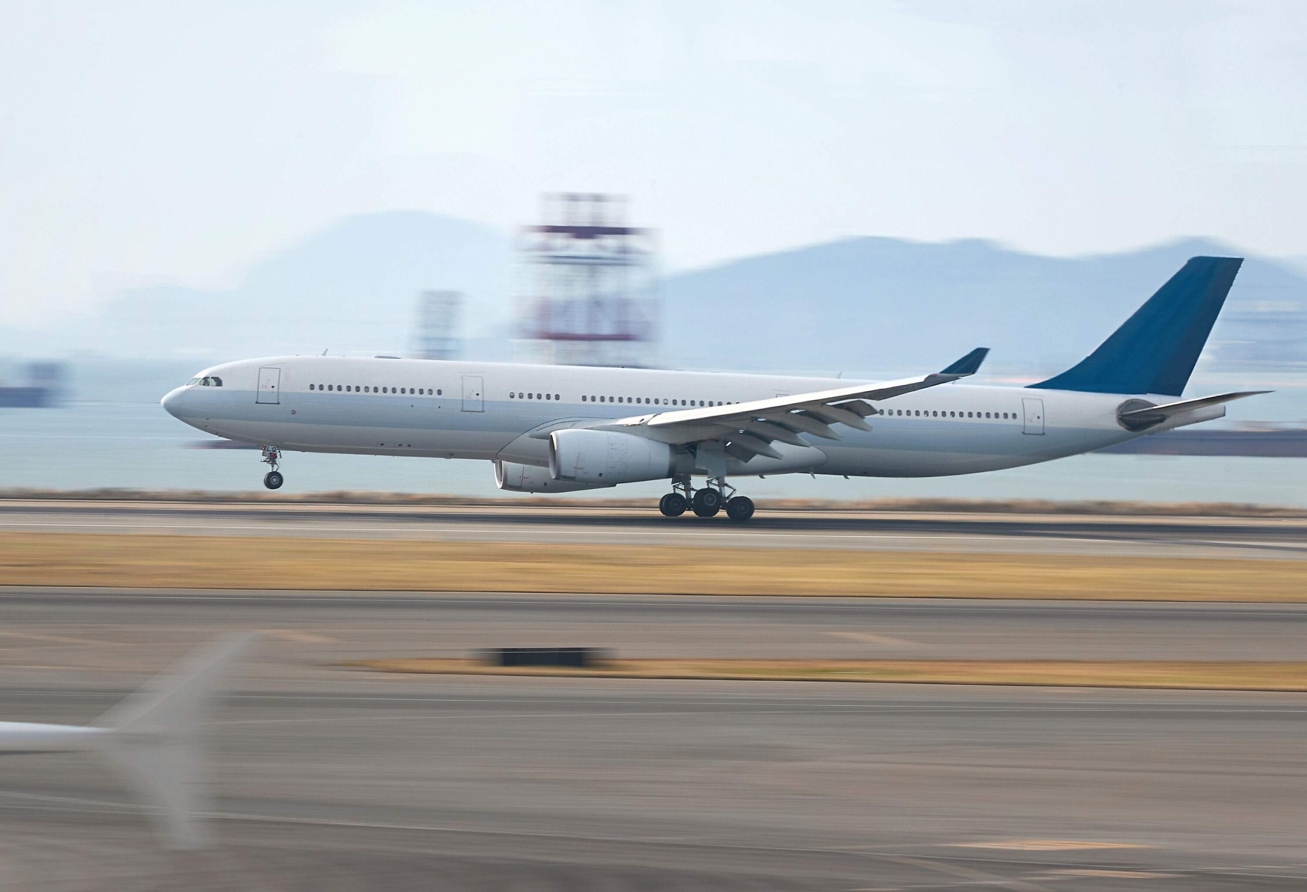 A white airplane landing on a runway at high speed.