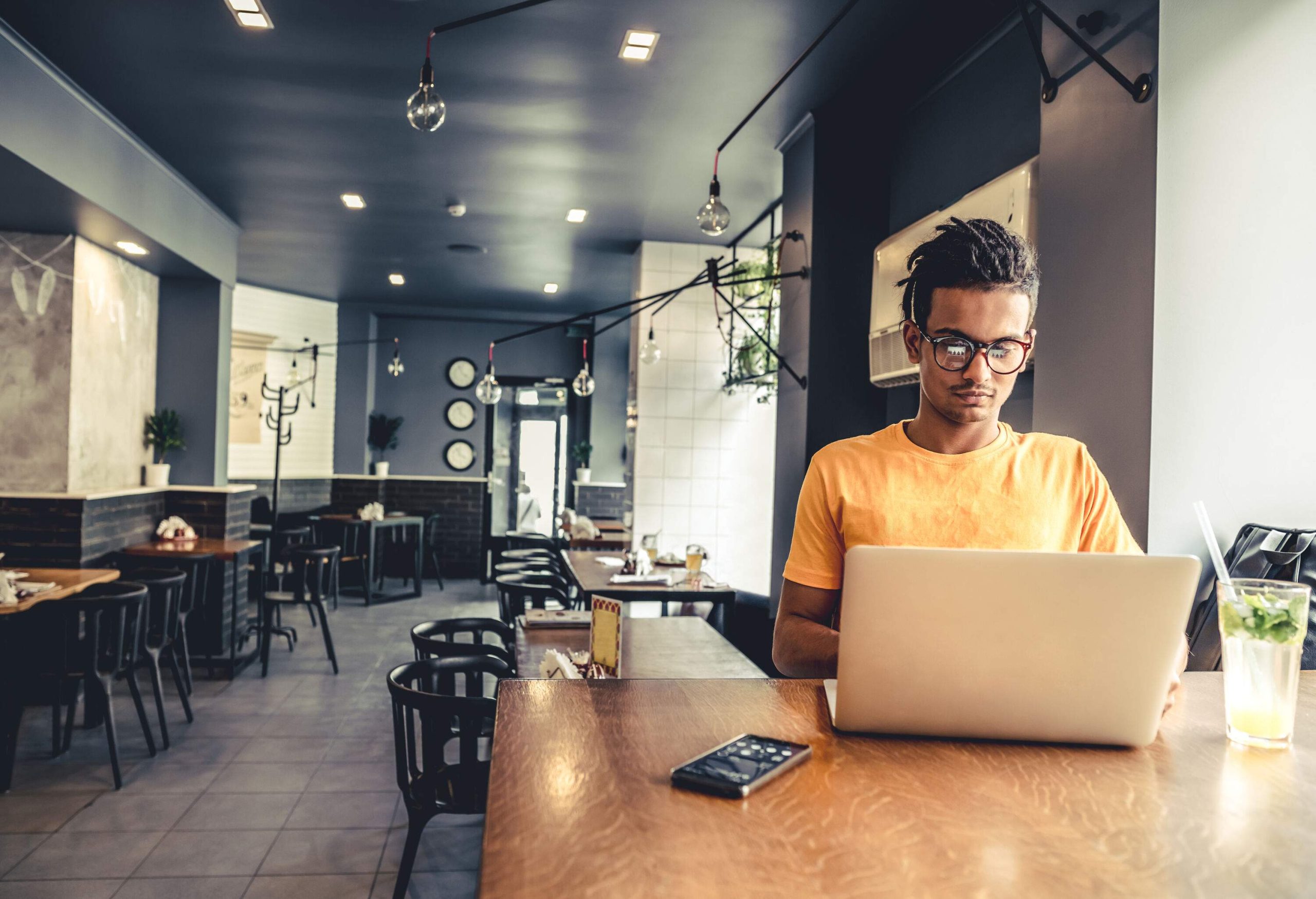 A lone man is busy working on his laptop in a cafe.