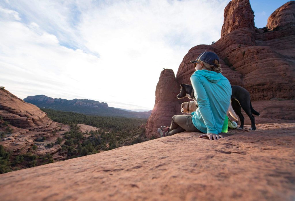 A woman and her two dogs taking a rest at some rocks in Sedona 