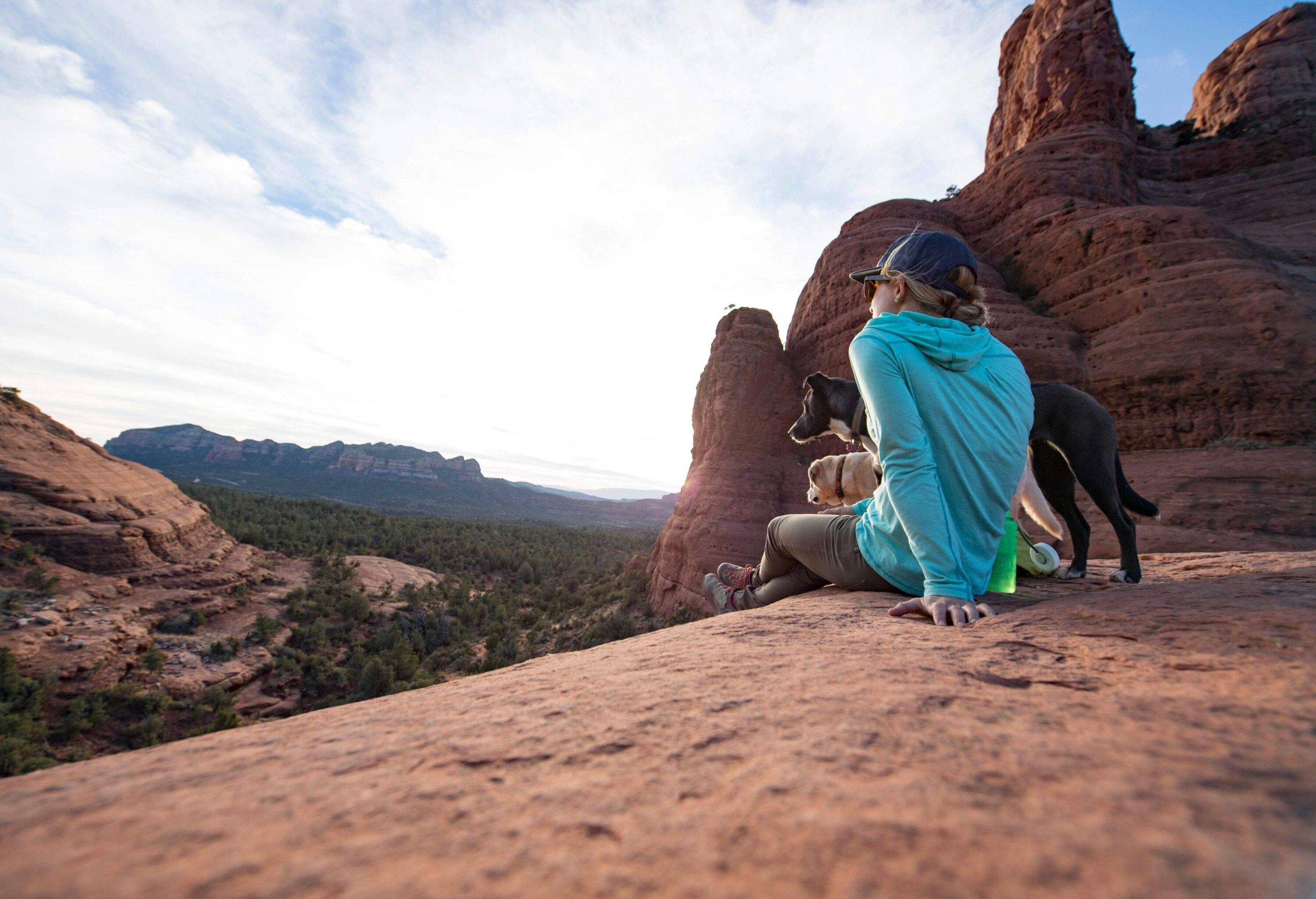 A woman and her two dogs taking a rest at some rocks in Sedona