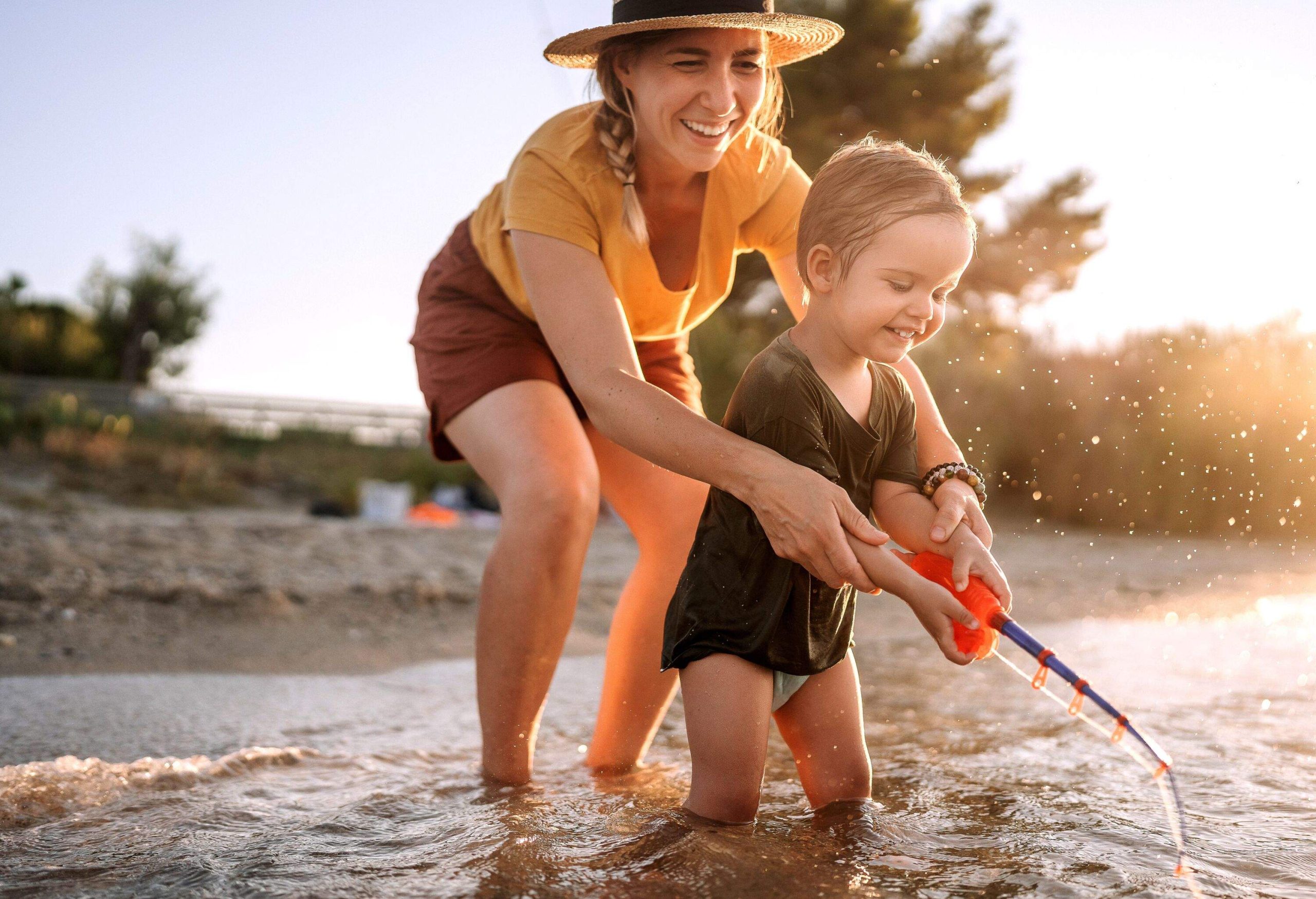 Mother and cute little toddler playing with fishing toy on the sea