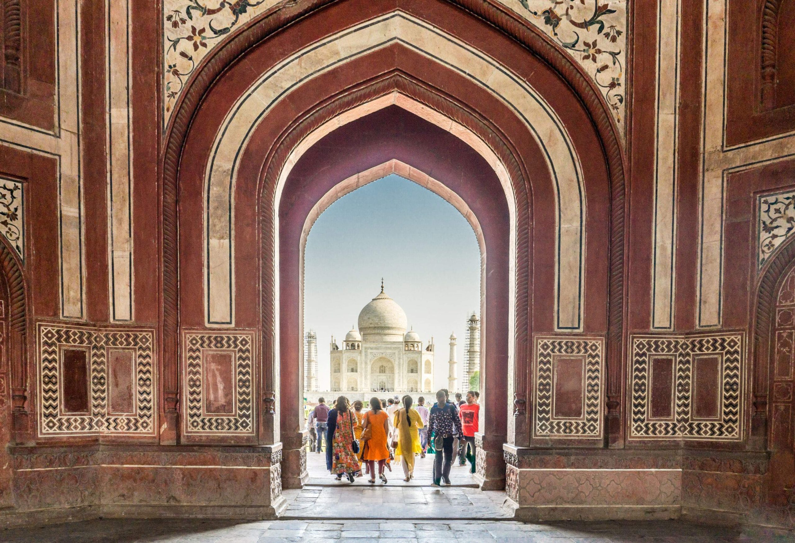 Many tourists visit the iconic Taj Mahal passing through the ornate pointed arch entranceway.
