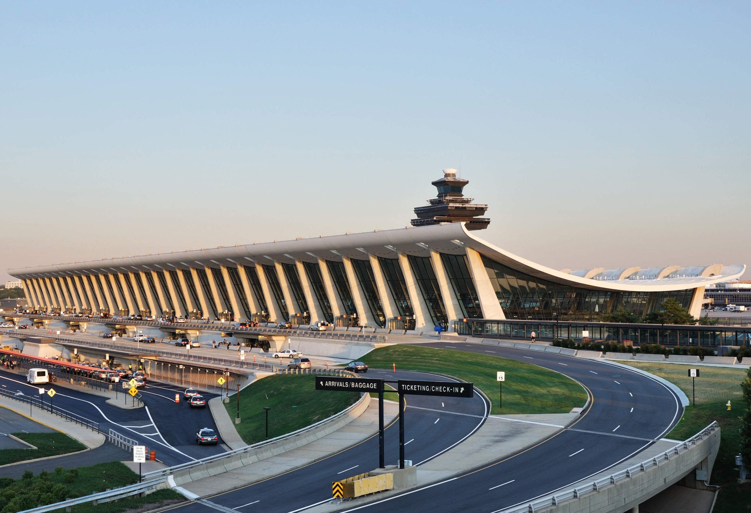 The main terminal of Washington Dulles International Airport is characterised by its iconic curved design and expansive glass windows, fronted by a series of roads leading to it.