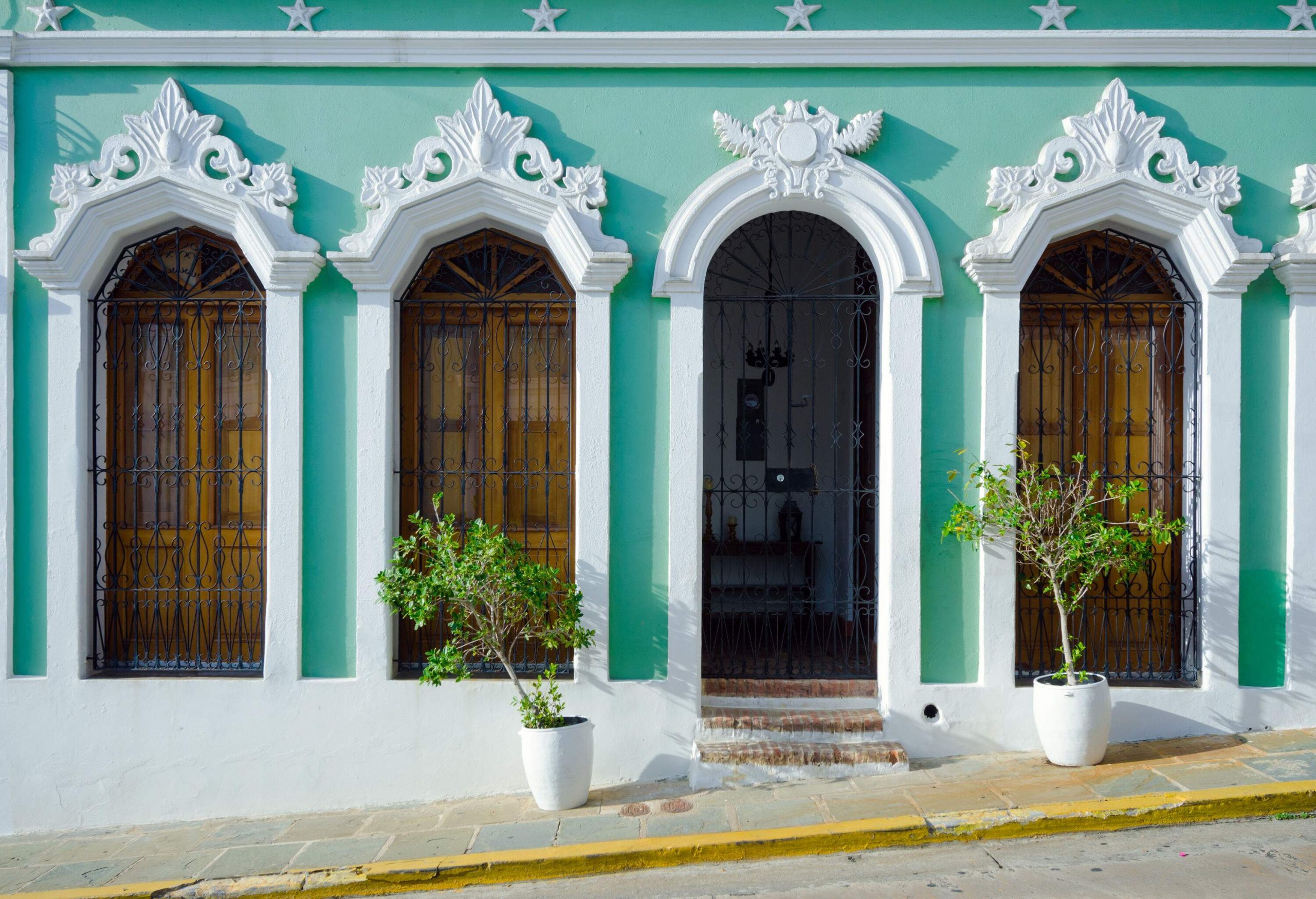 A building with light green exterior walls and white arched mouldings around its windows and doorway.