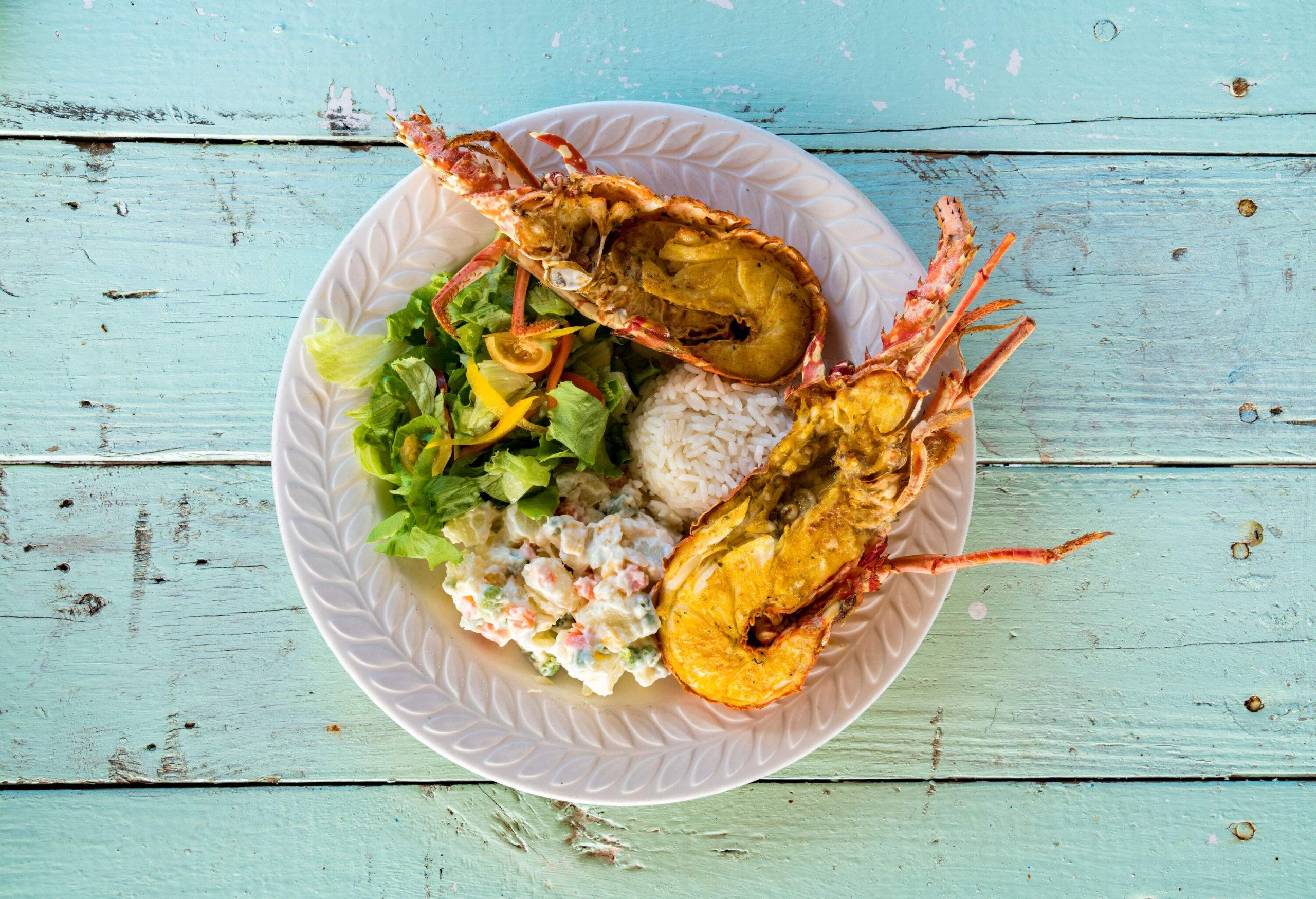 A hearty meal consisting of lobster, two varieties of salad, and white rice.