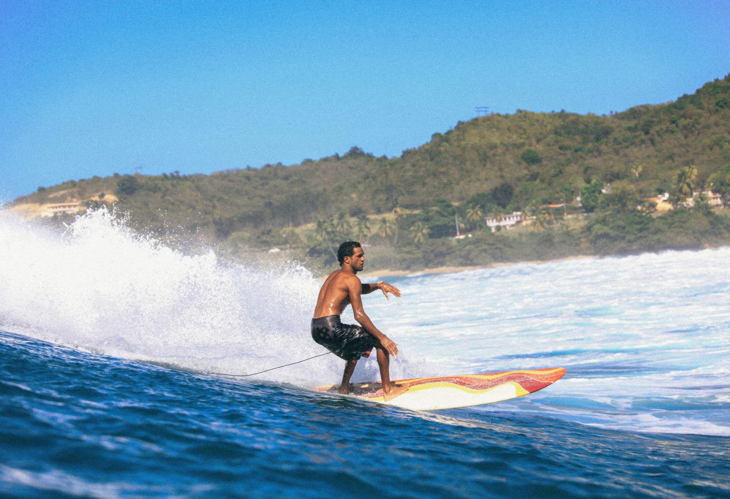 A man skillfully surfs on the wavy beach by the lush island.