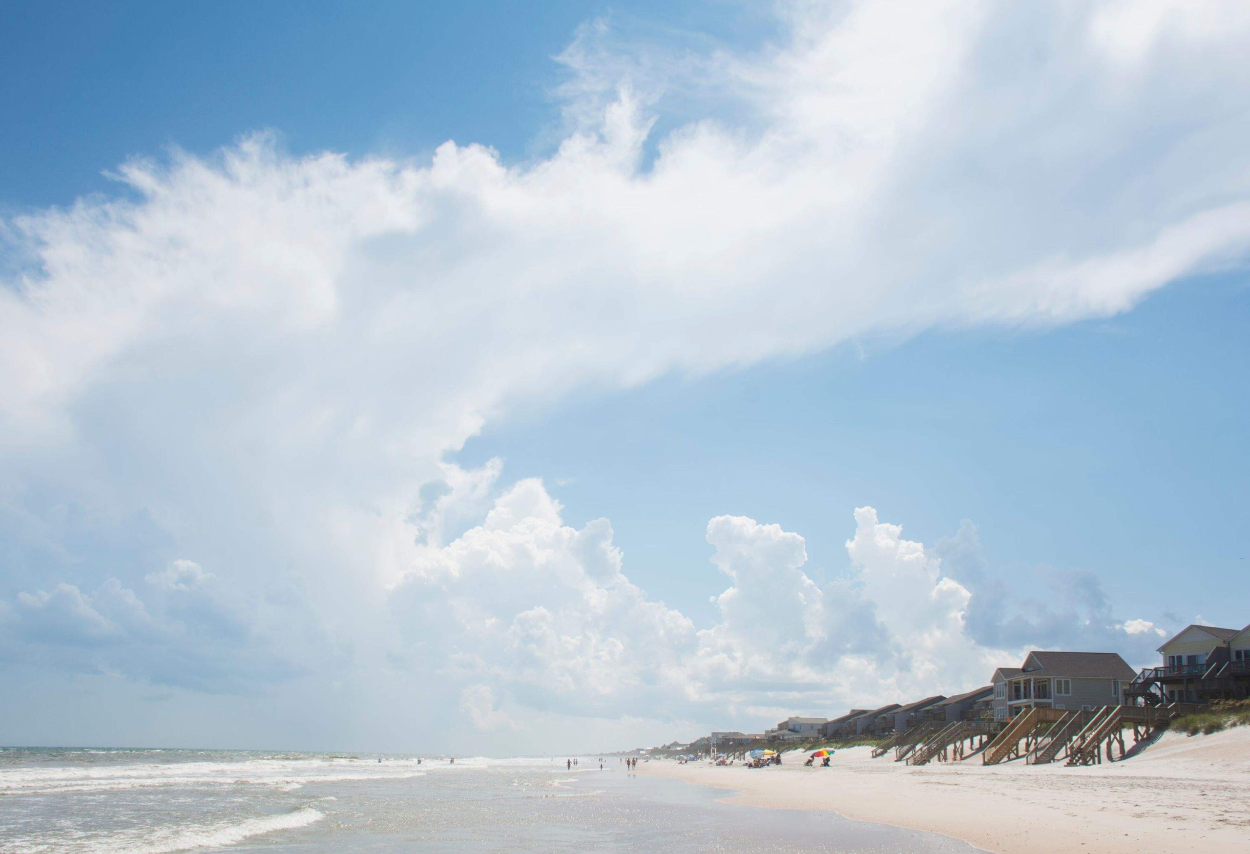 a wide beach shore with houses facing the sea