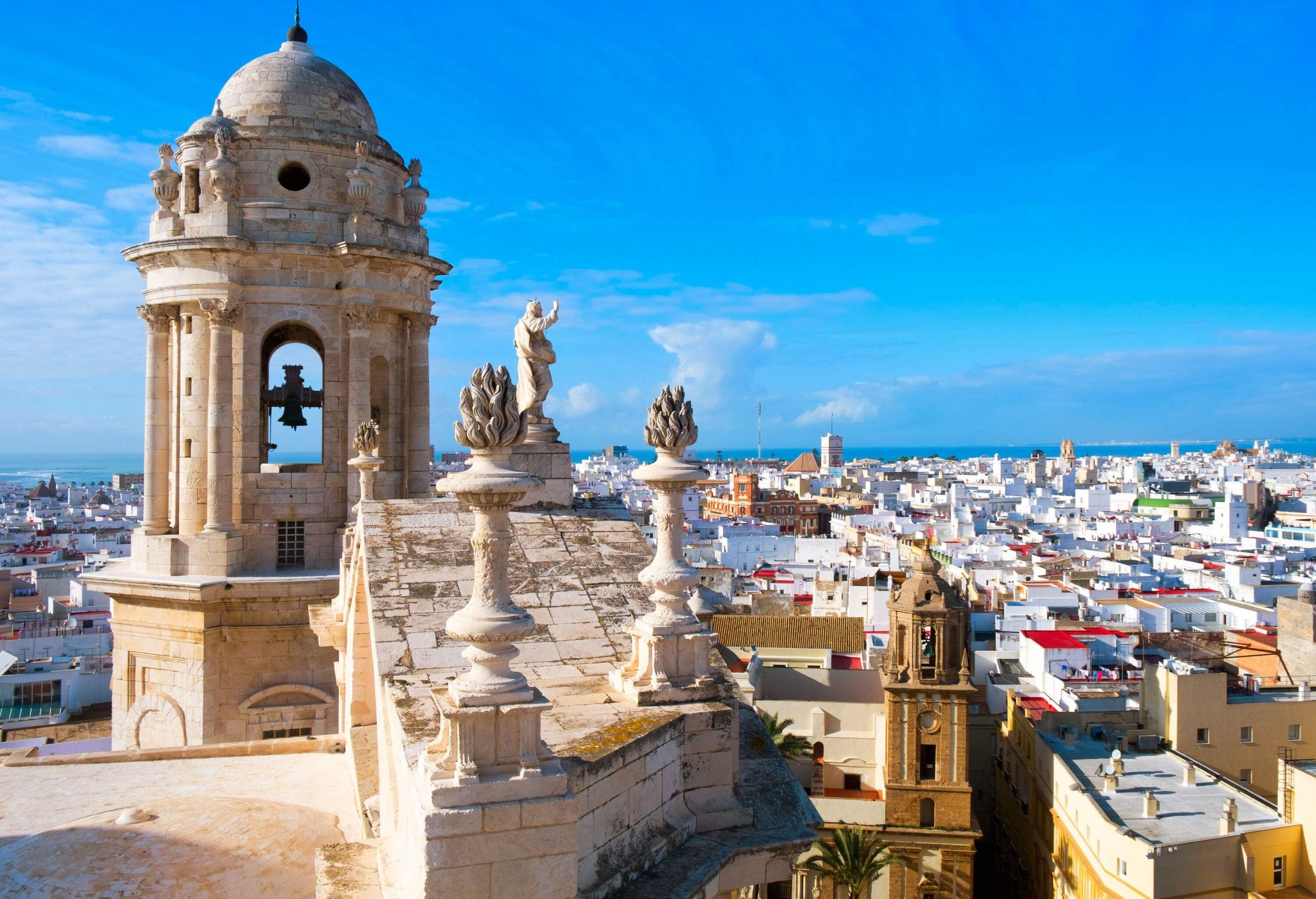 A bell tower with sculptures overlooking the rooftops of city buildings.