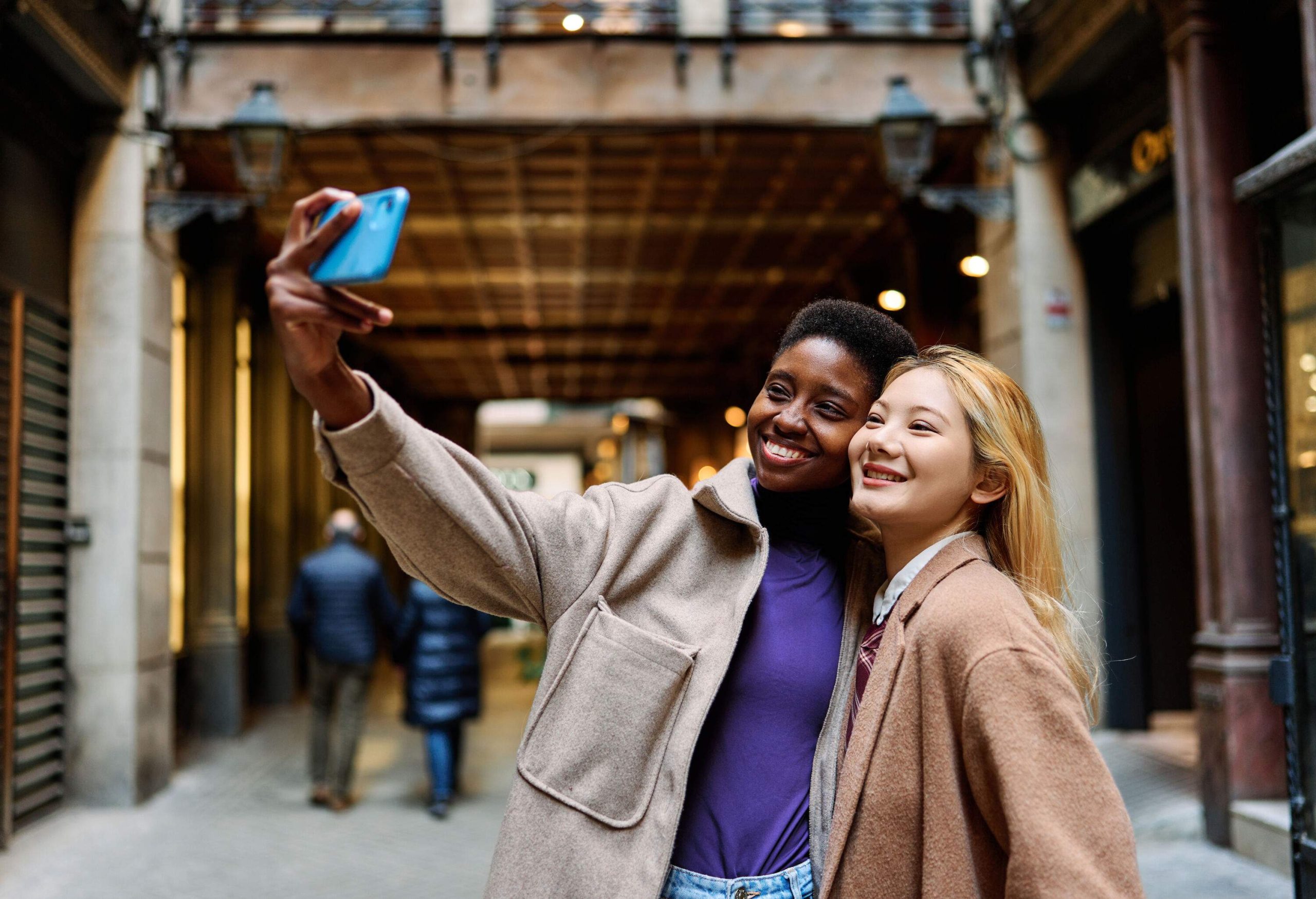 Two women standing on the street, posing for a selfie.
