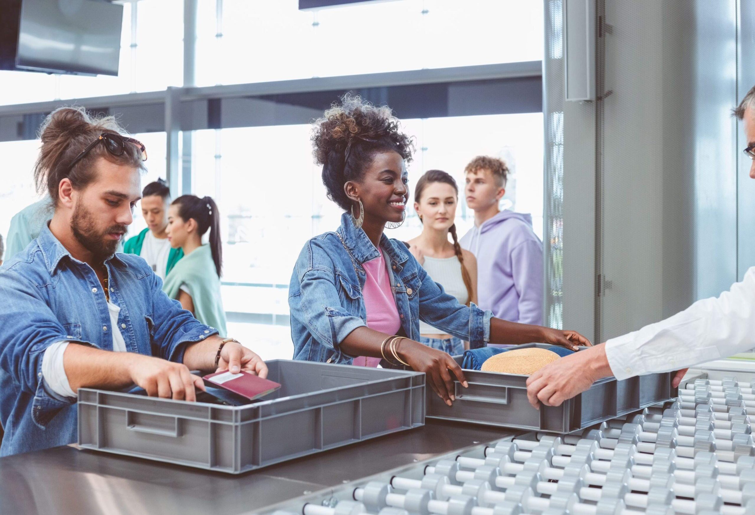 Multiracial group of passengers passing by airport security check.