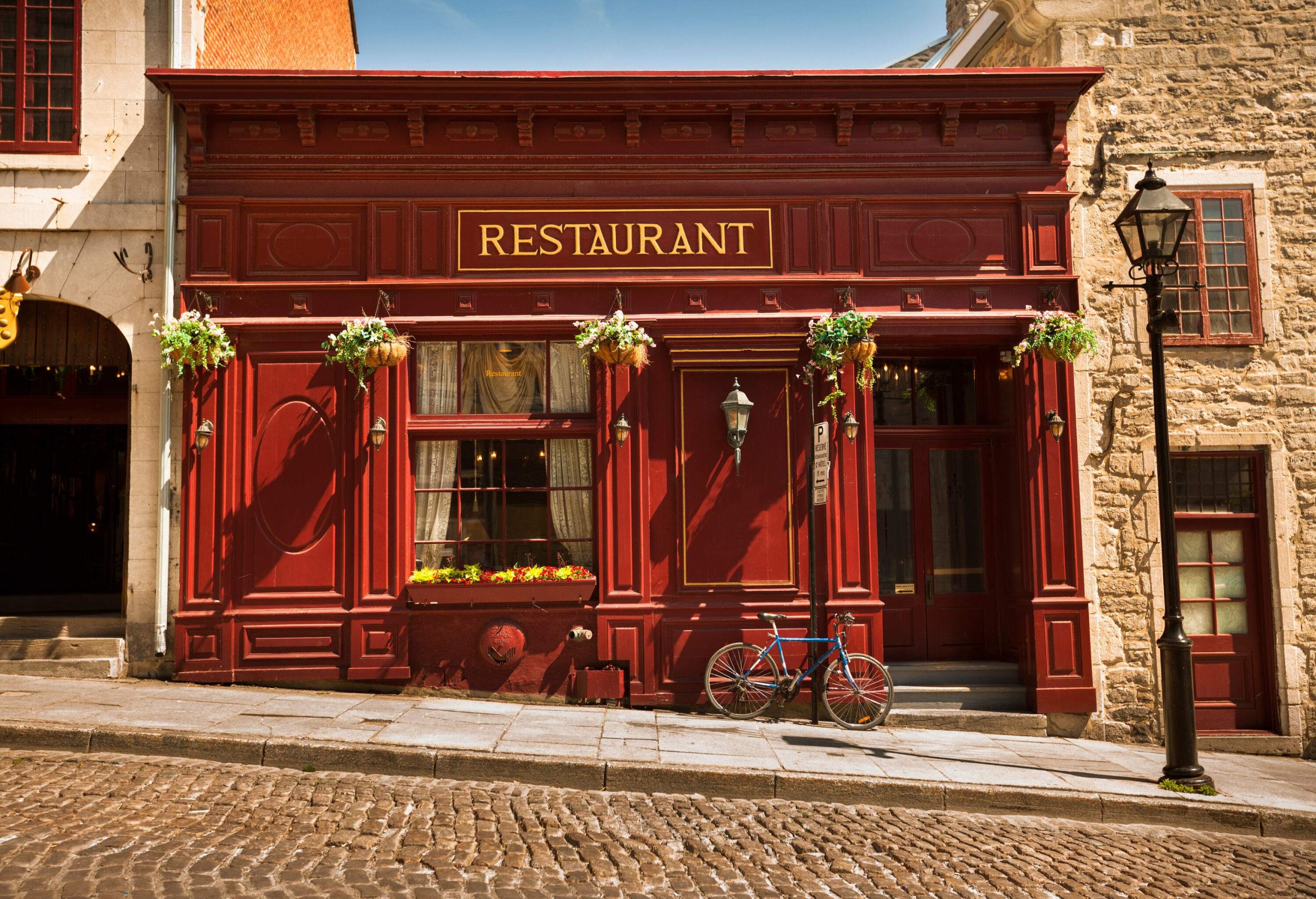 A classic French-style restaurant with a bicycle parked against the exterior wall.
