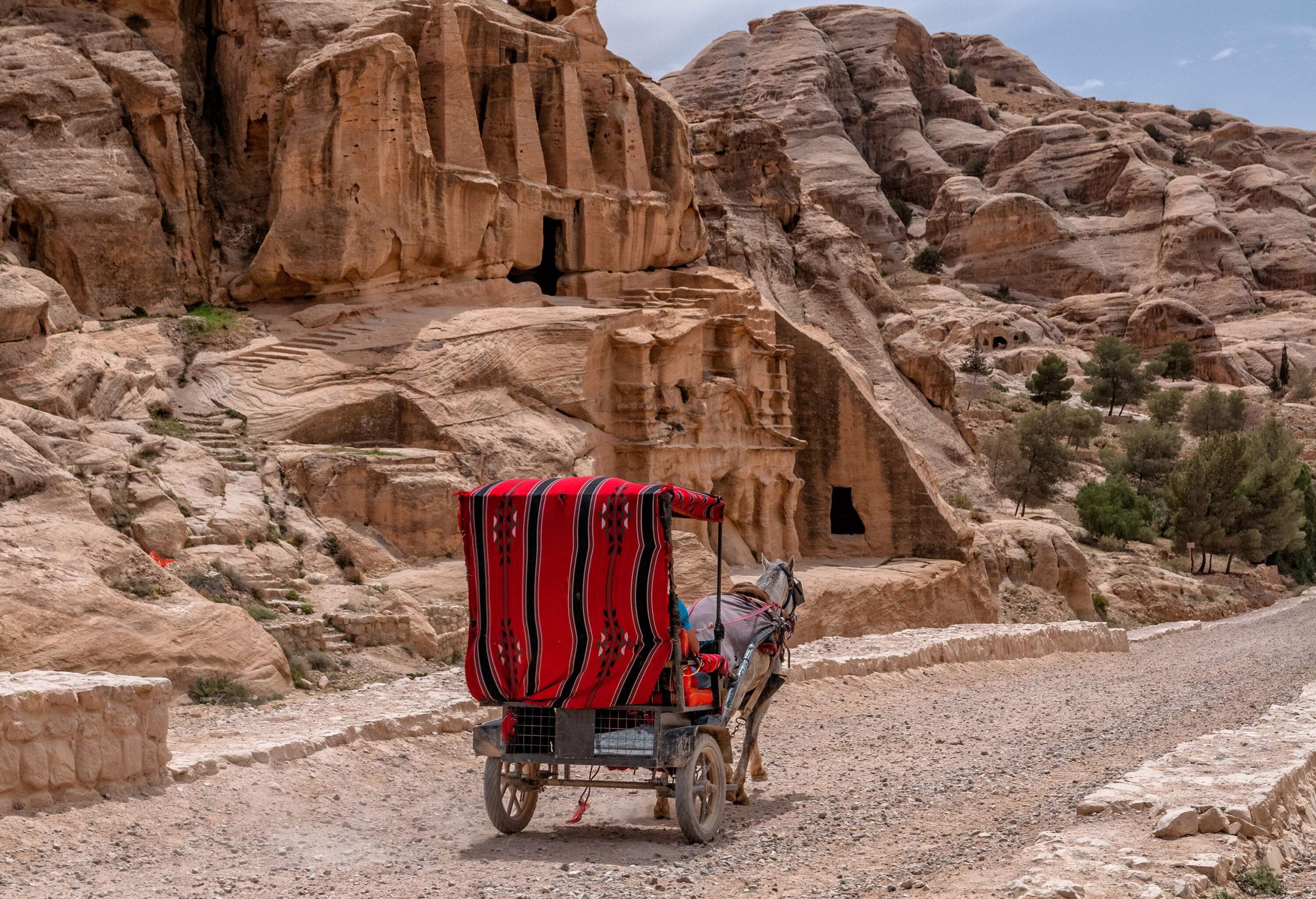 A carriage travels along a road amidst the granite rock formations of the desert.