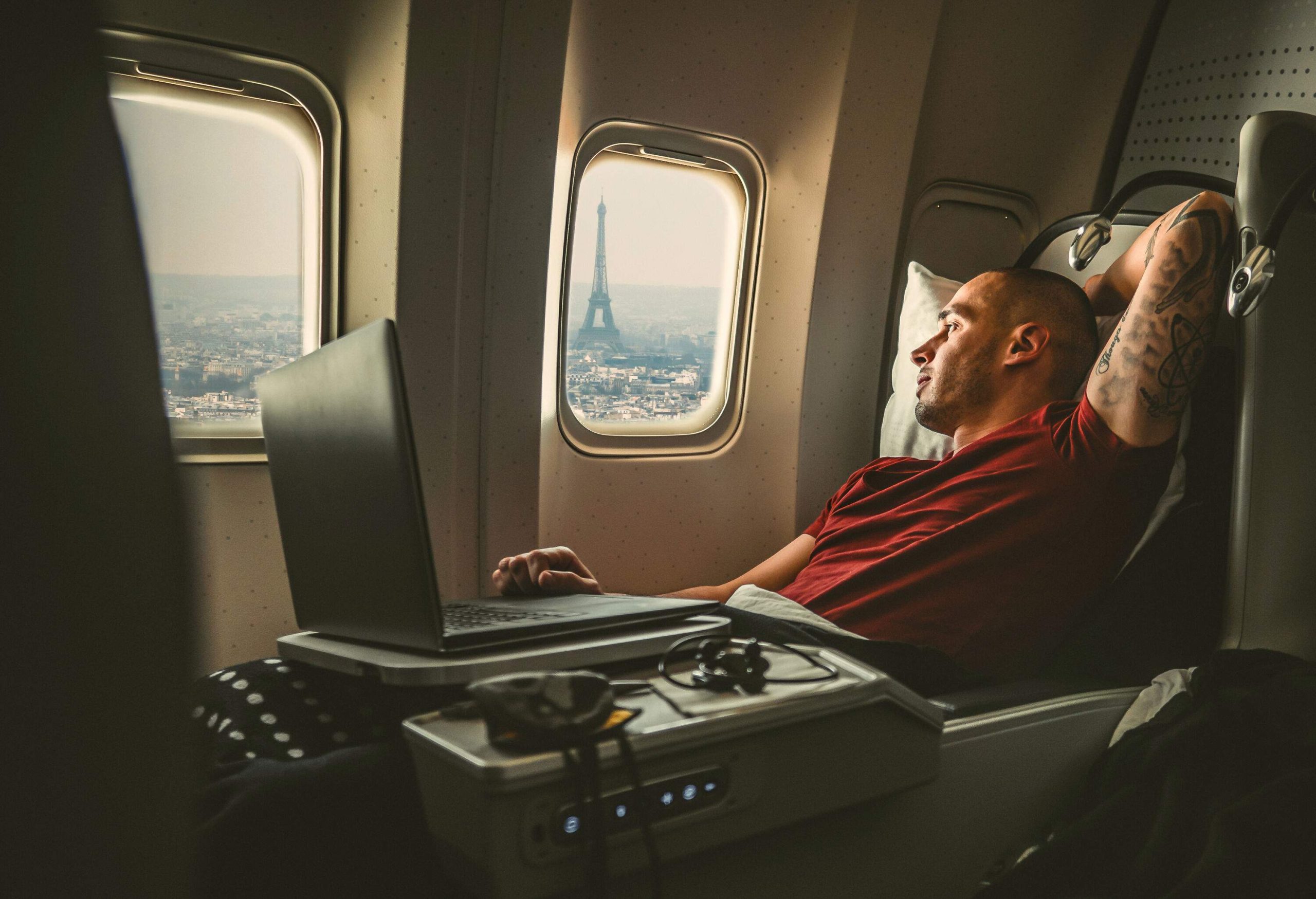 A person is seated in an aeroplane, gazing out the window at the Eiffel Tower.