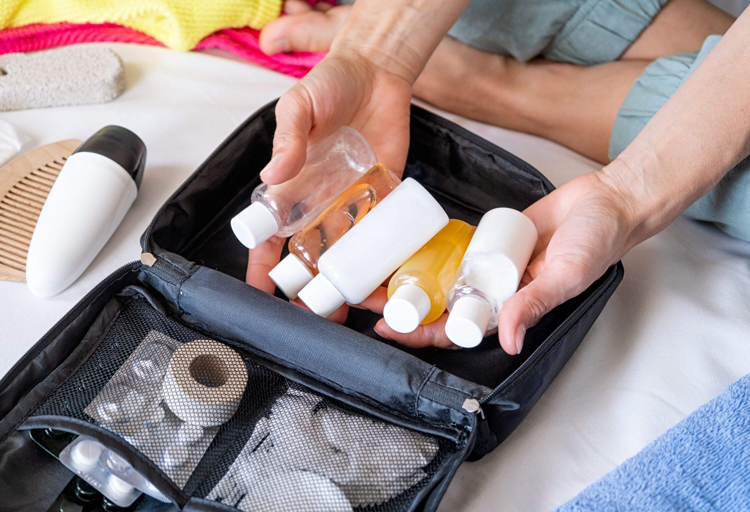 Travel cosmetics kit with bottles, pills and cosmetics on bed , top view