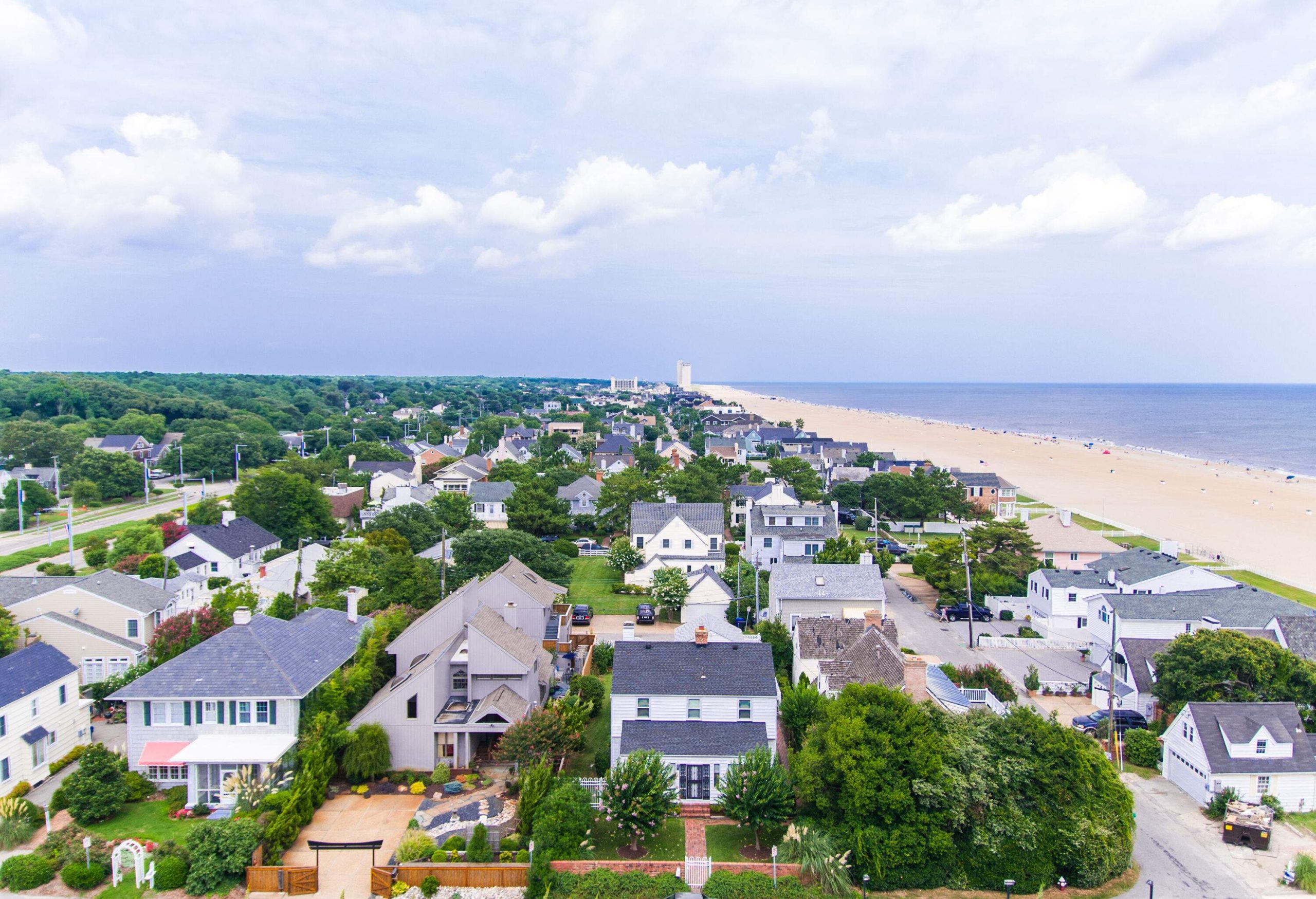 Nestled along the coastline, the charming beachfront town features streets lined with picturesque trees, leading towards the inviting expanse of white sand beach that stretches as far as the eye can see.