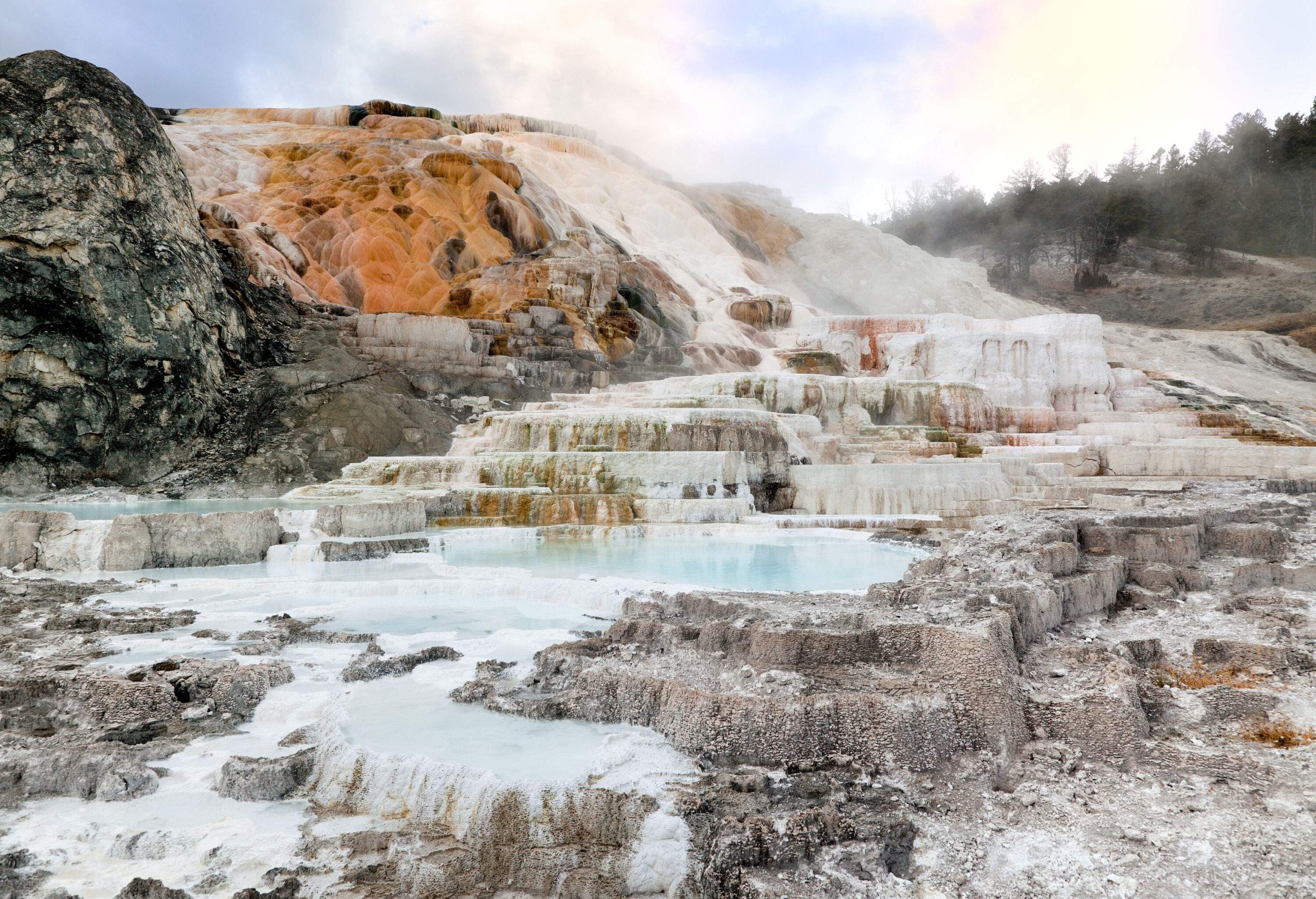 A hill with tiered rock formations covered in white mineral deposits.