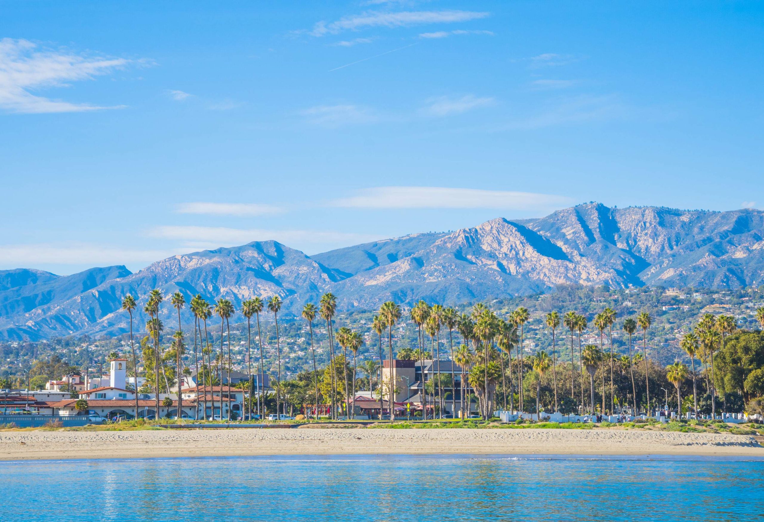 Coastal cityscape with a chain of mountains in the background.