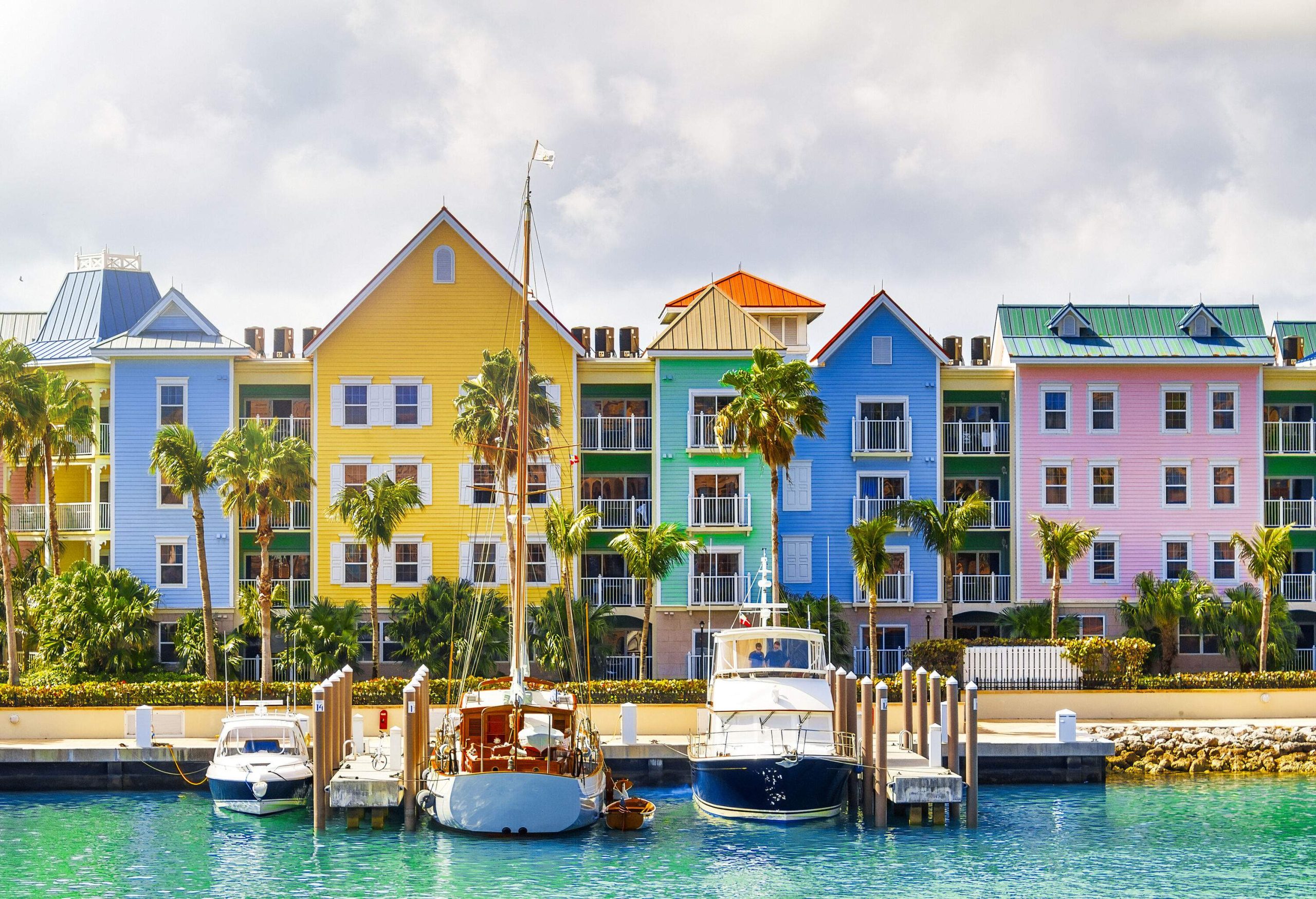 Colourful and modern townhouses on the coastline with moored yachts on the turquoise sea.