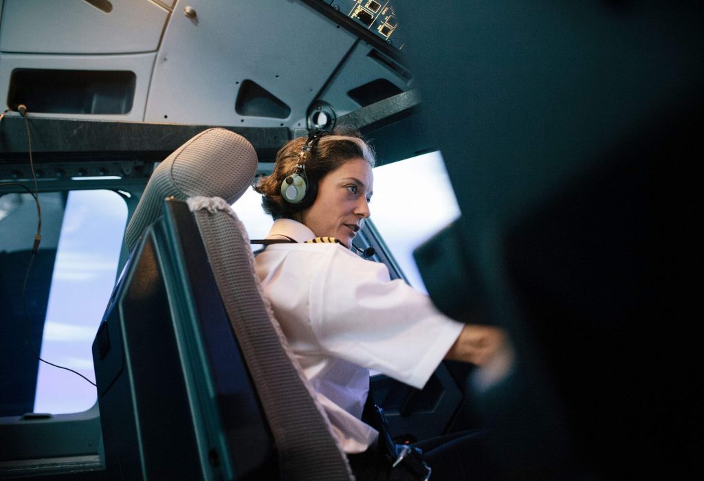 A female flight instructor sits in the cockpit while giving instructions.