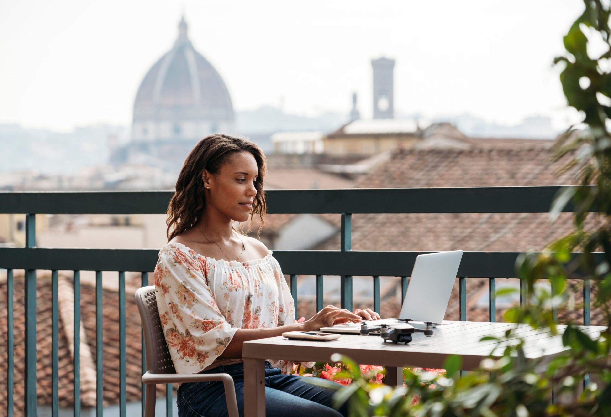 Remote worker sat in a cafe on a balcony overlooking the city of Florence