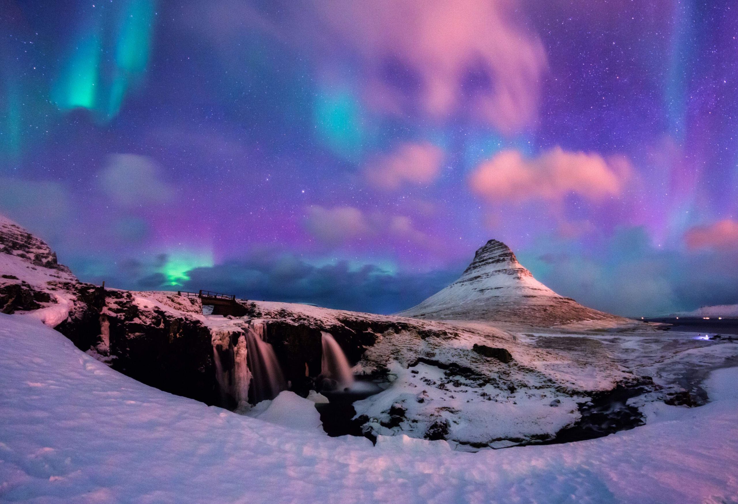 A vibrant night sky hovering over the snow-covered Kirkjufell Mountain.