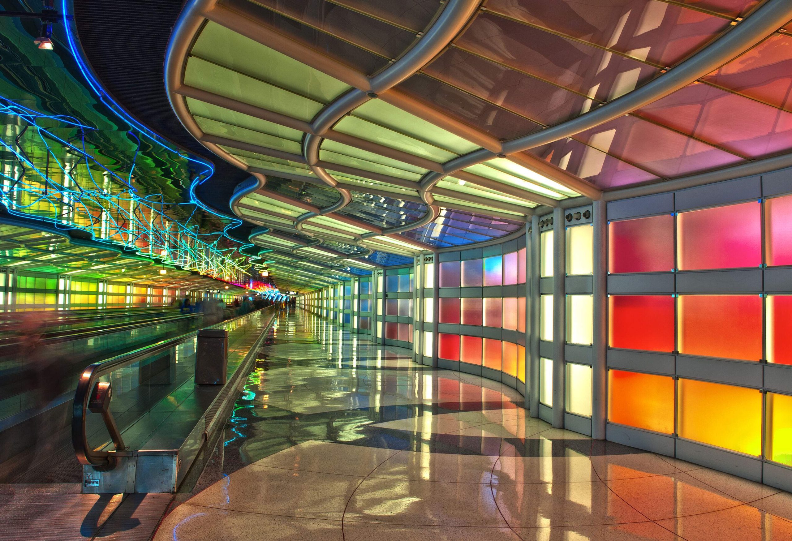 The inside of a passenger tunnel features colourful walls and winding and bright ceilings.