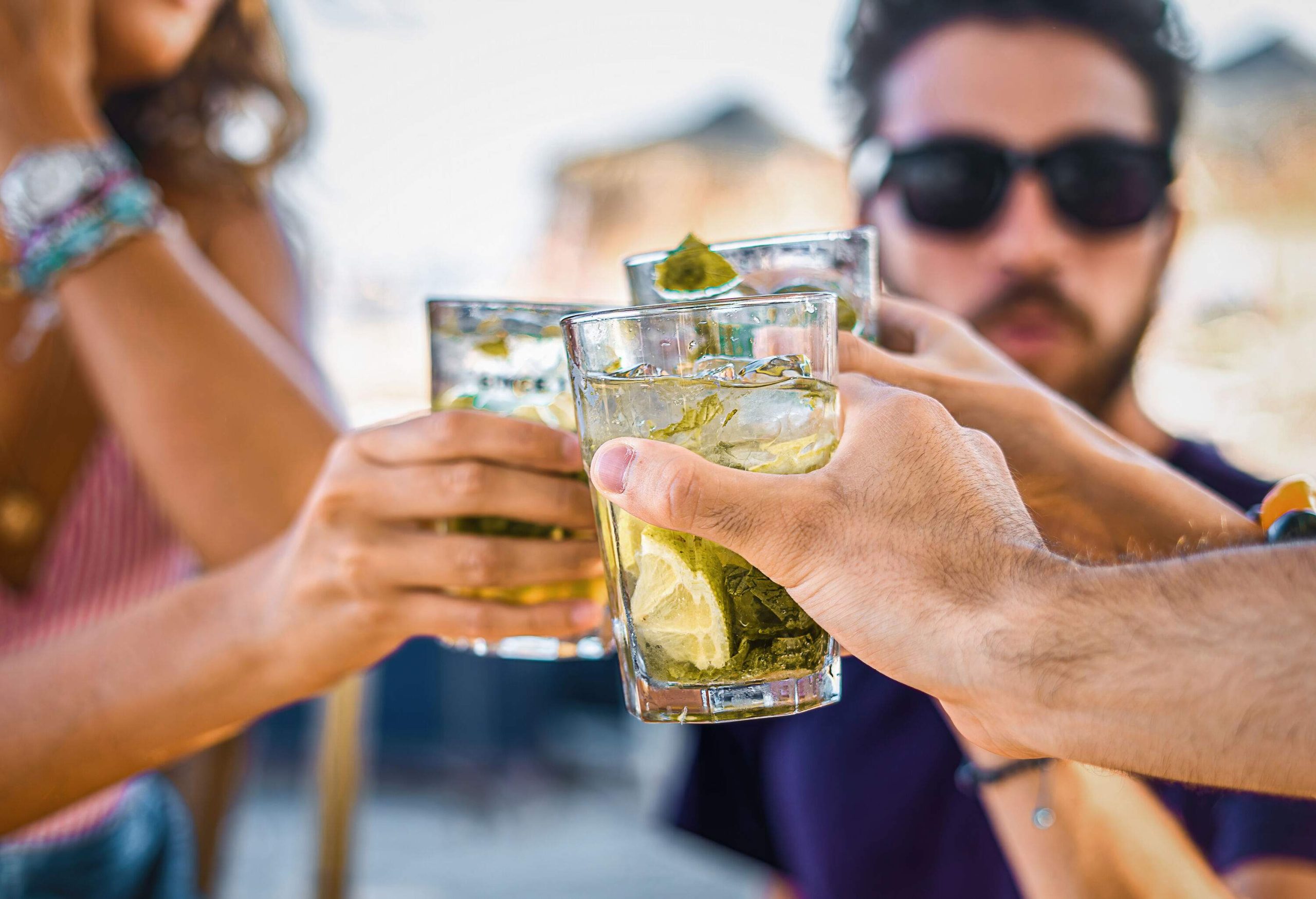 Hands making a toast with glasses of cocktails.