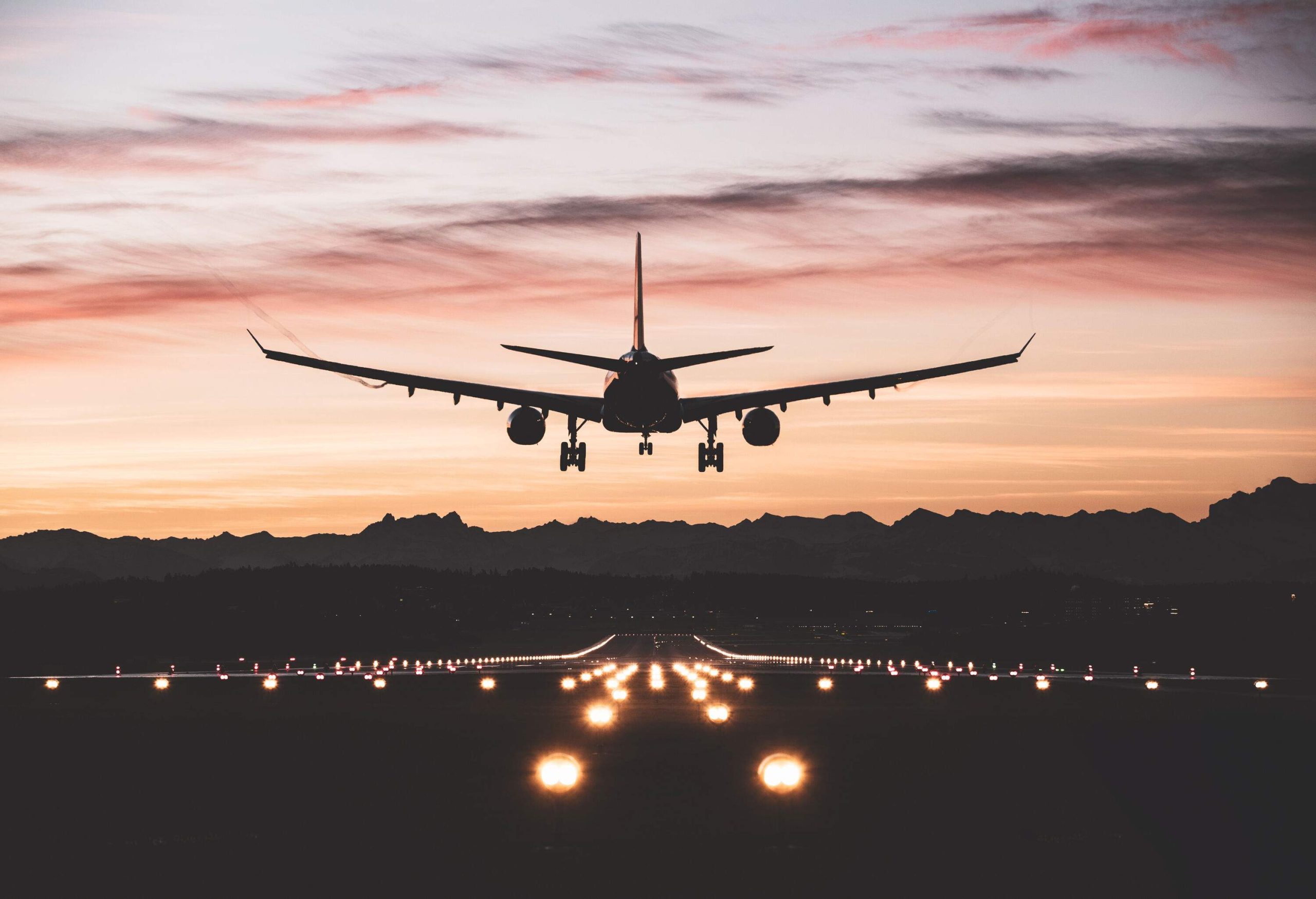 An airplane descending into a runway outlined by edge lights.