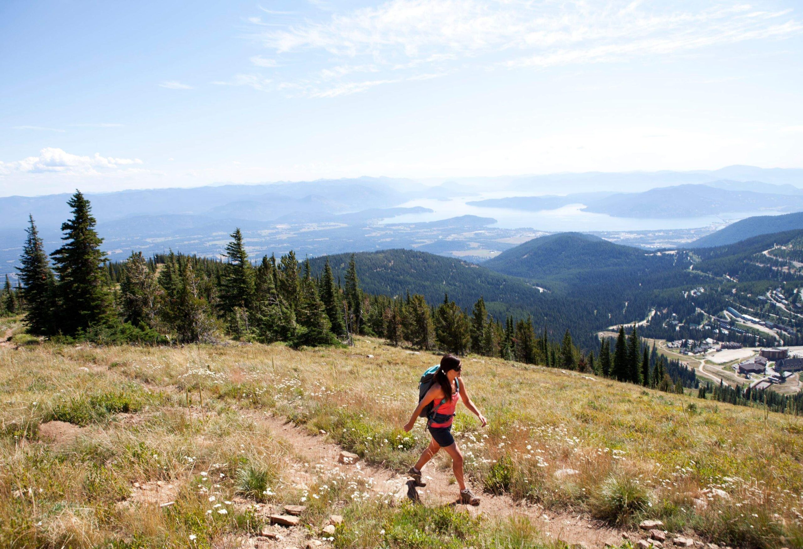 A woman hiking up Mt. Schweitzer while overlooking Sandpoint Idaho and Lake Pend Orielle