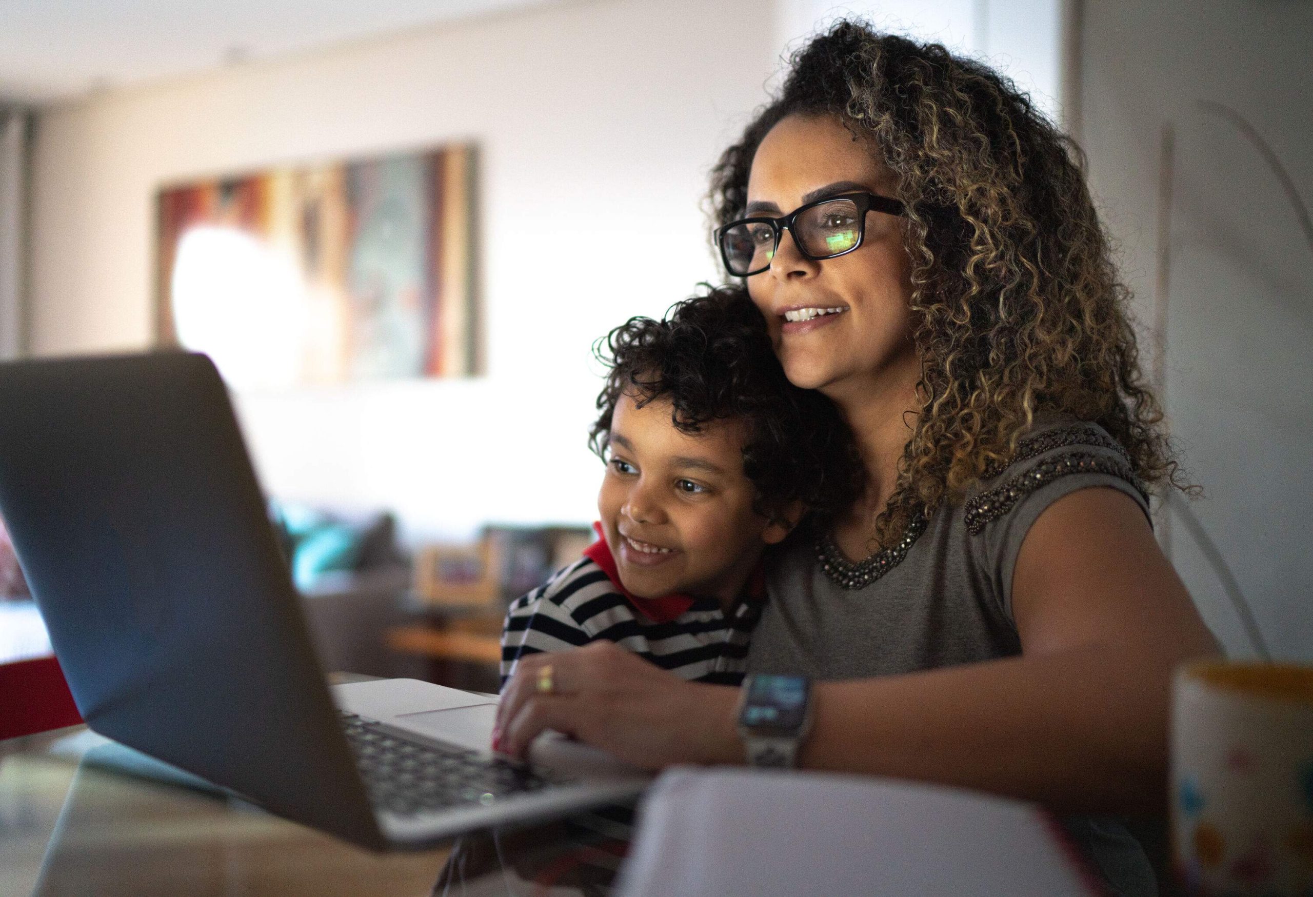 A mother and son in their home, looking at a laptop.