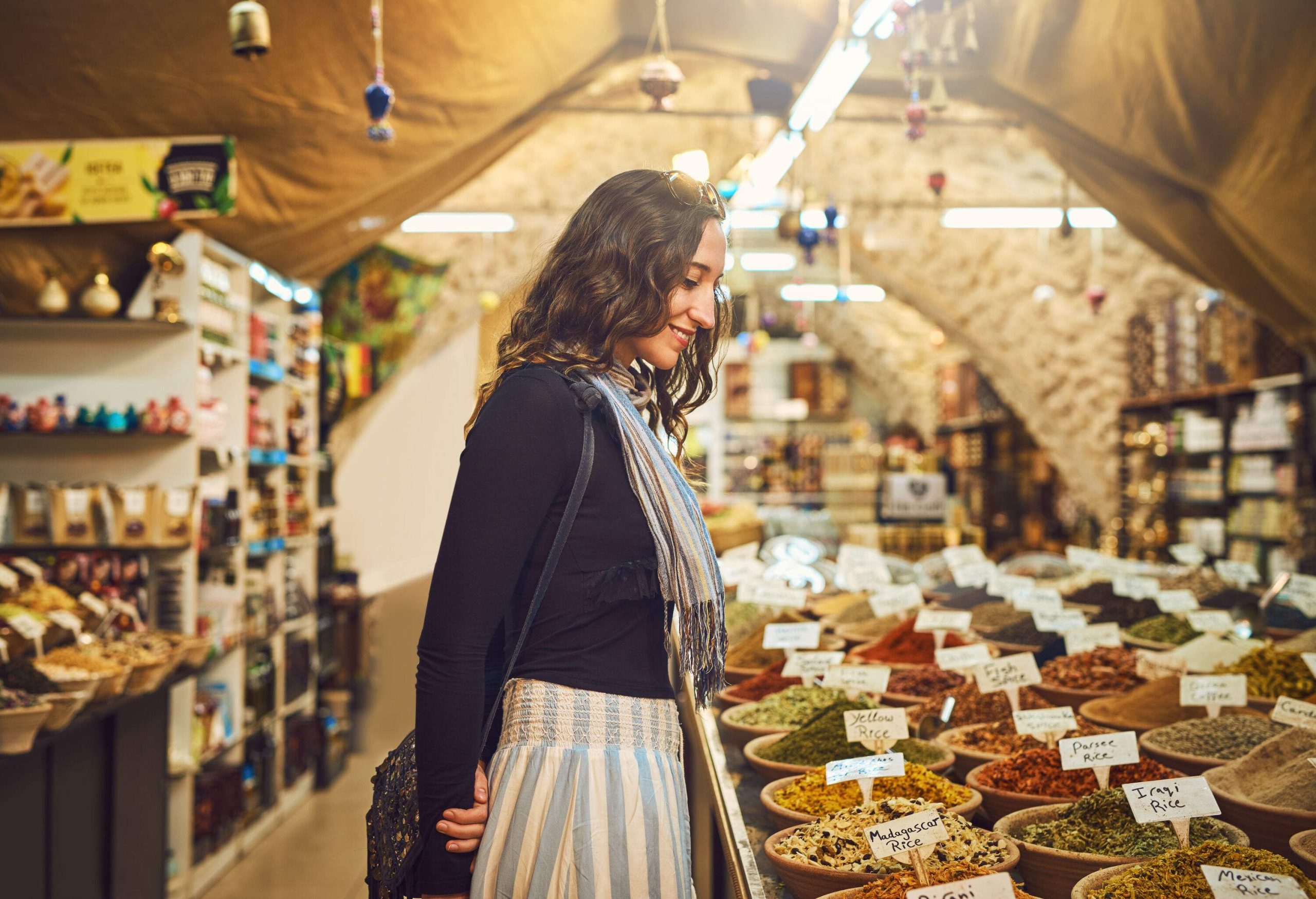 A young lady staring at the spices and herbs displayed in a store.
