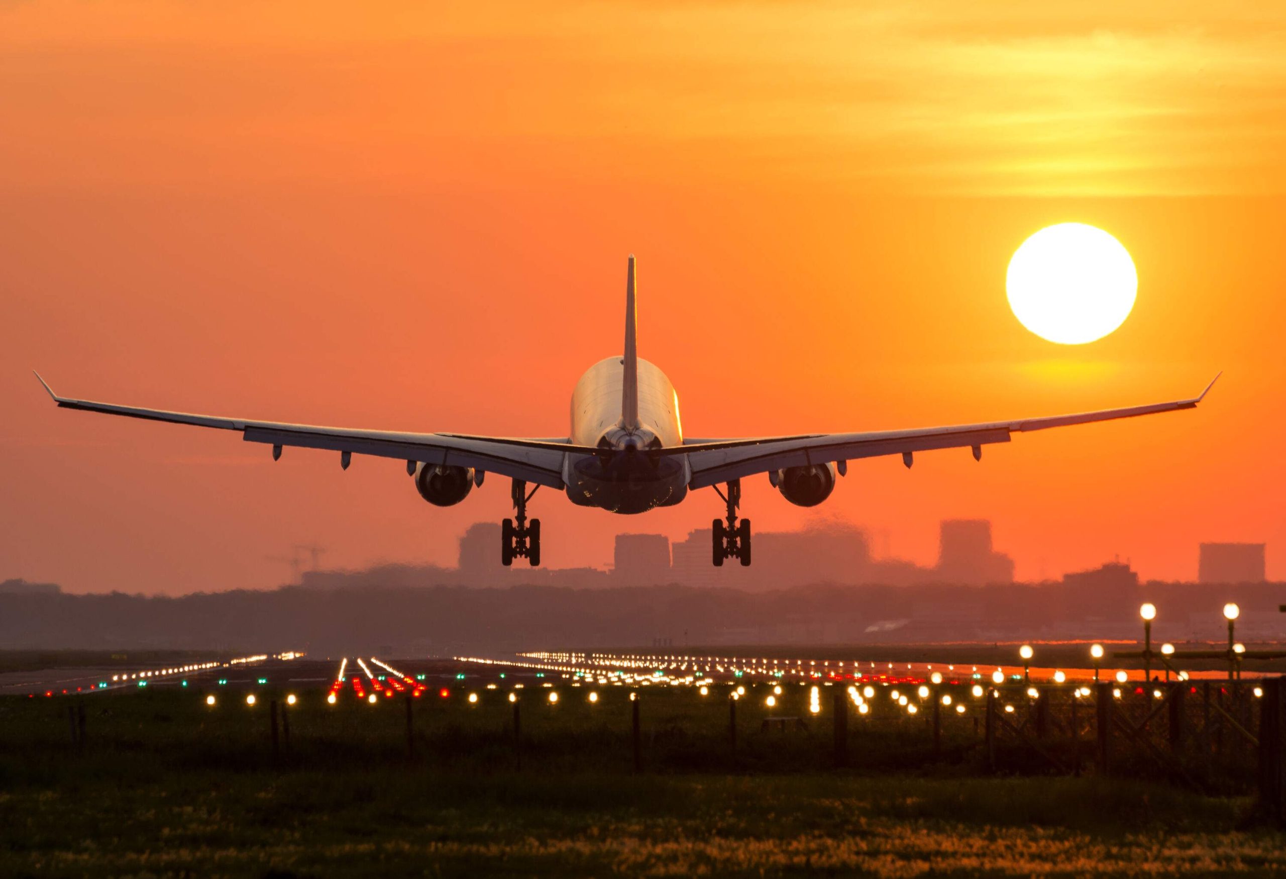 A passenger plane gracefully lands on a beautifully lit runway during a stunning sunrise.