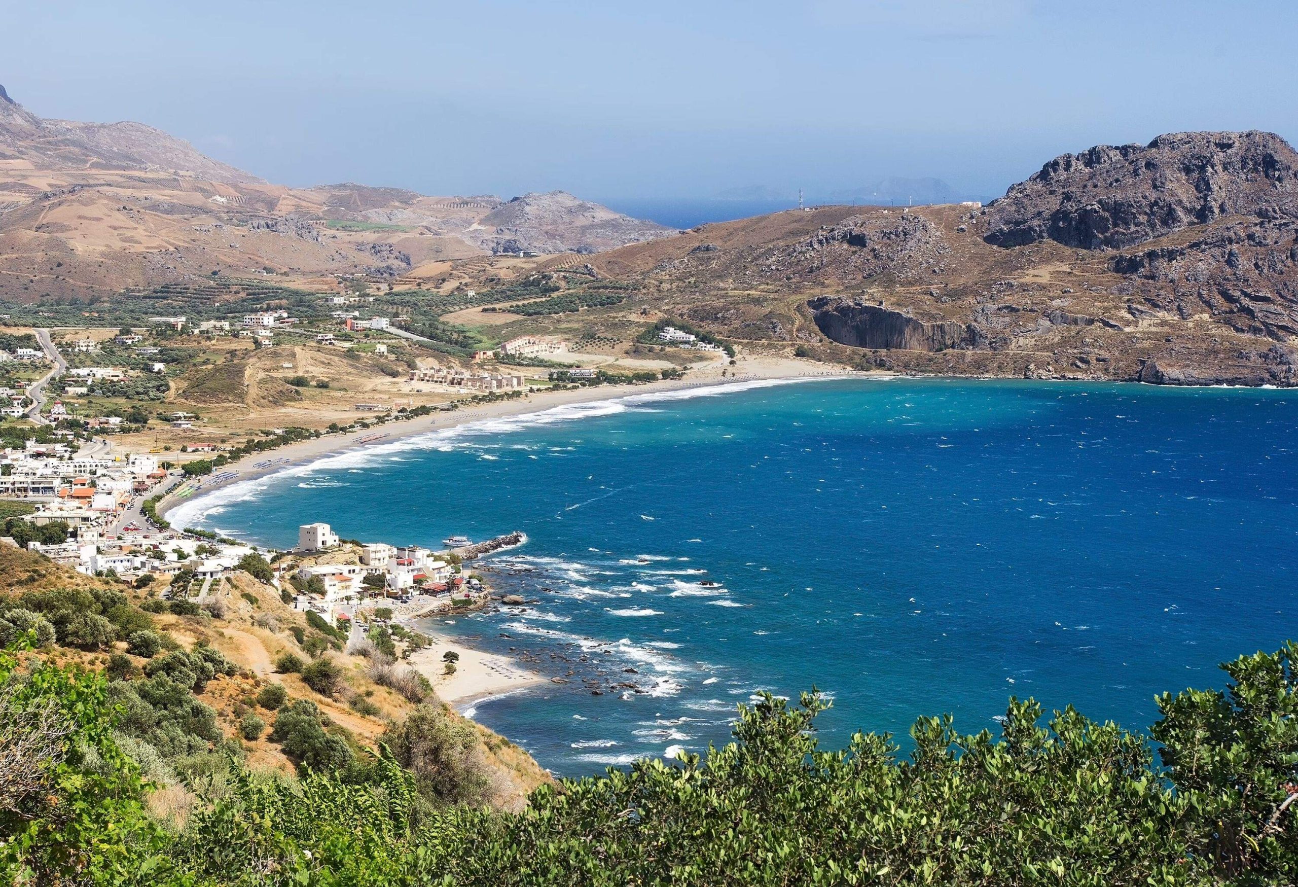 A small town on the coast surrounded by rocky mountains and sandy hills.