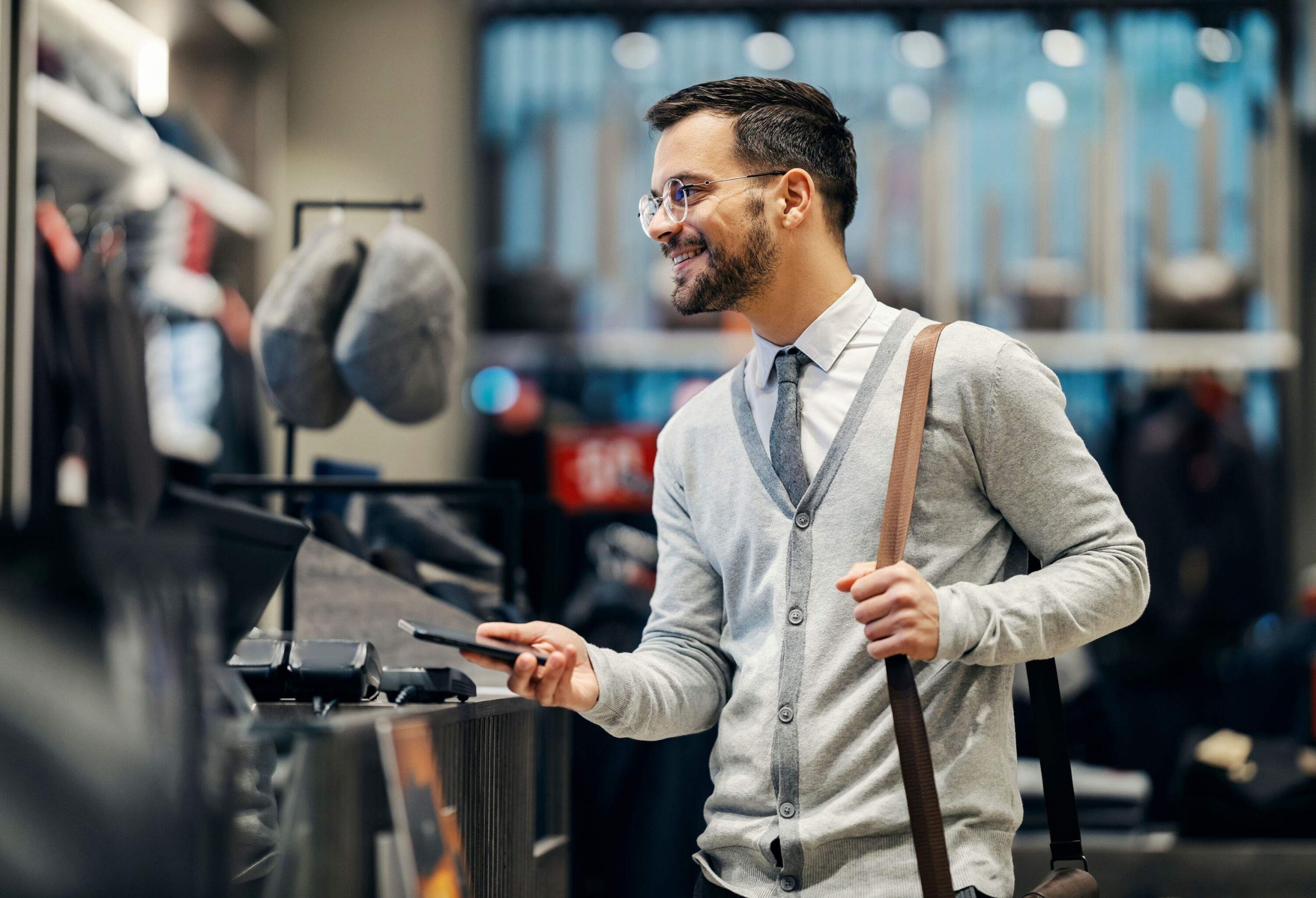 A male shopper paying online at the counter in a clothing store.