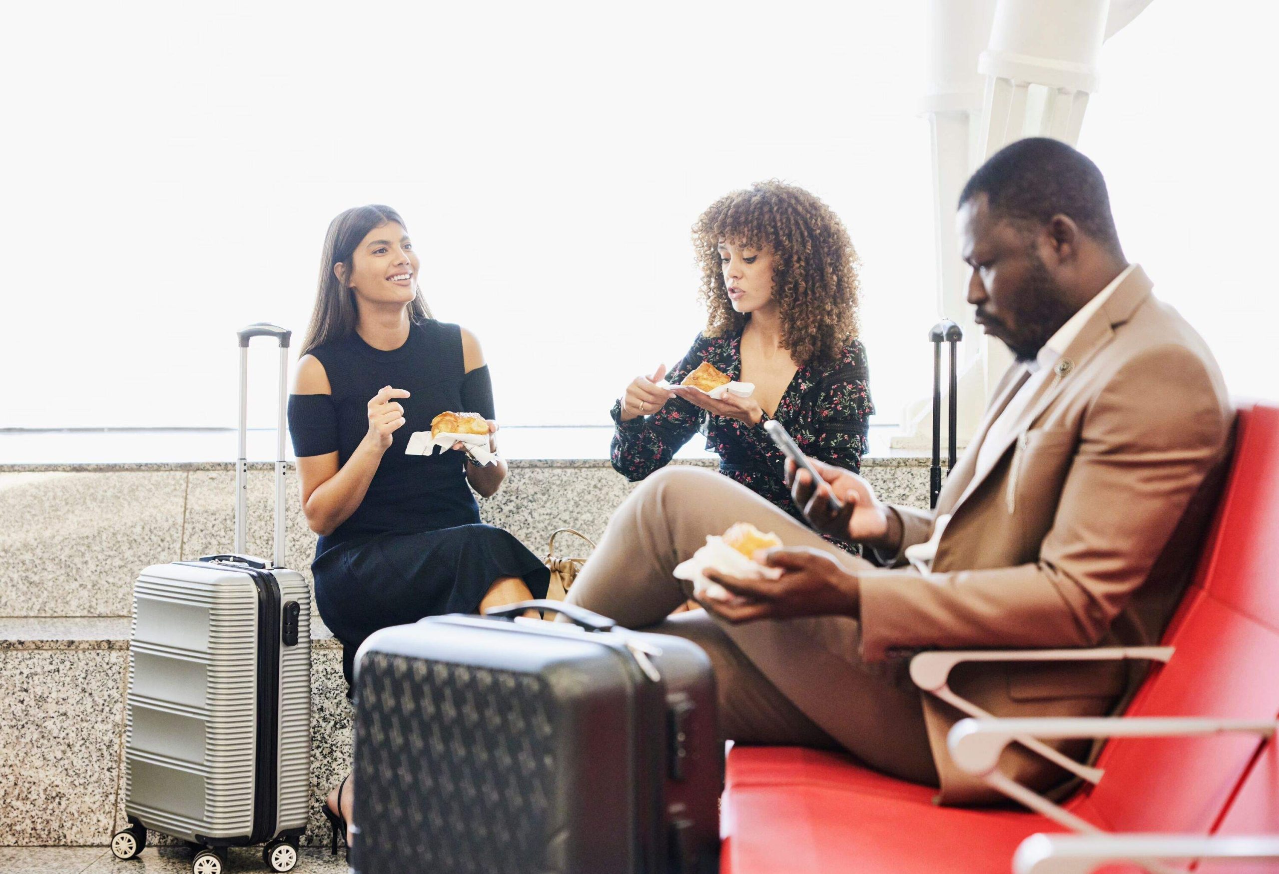 Medium shot of friends in discussion while waiting for flight in departure area of airport terminal