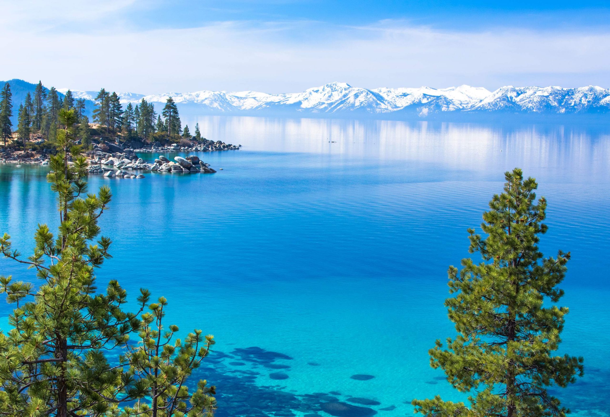 A turquoise-watered lake with a snow-covered mountain range in the background.
