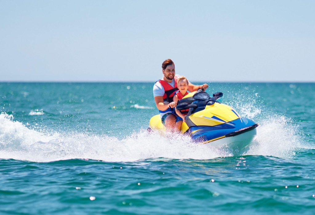 A father and son enjoying themselves while jet skiing in the water.